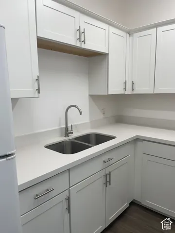 Kitchen featuring white shaker-style cabinetry, light-toned countertops, a stainless steel double-basin sink, and a high-arc faucet