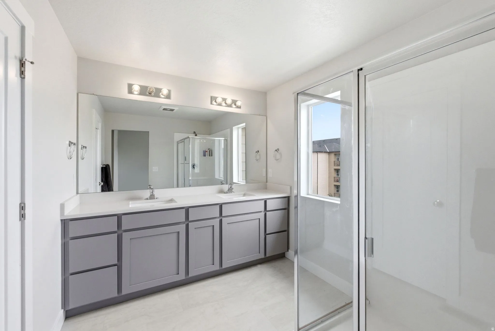 Double vanity featuring gray shaker-style cabinetry, white countertops, and dual undermount sinks with chrome fixtures