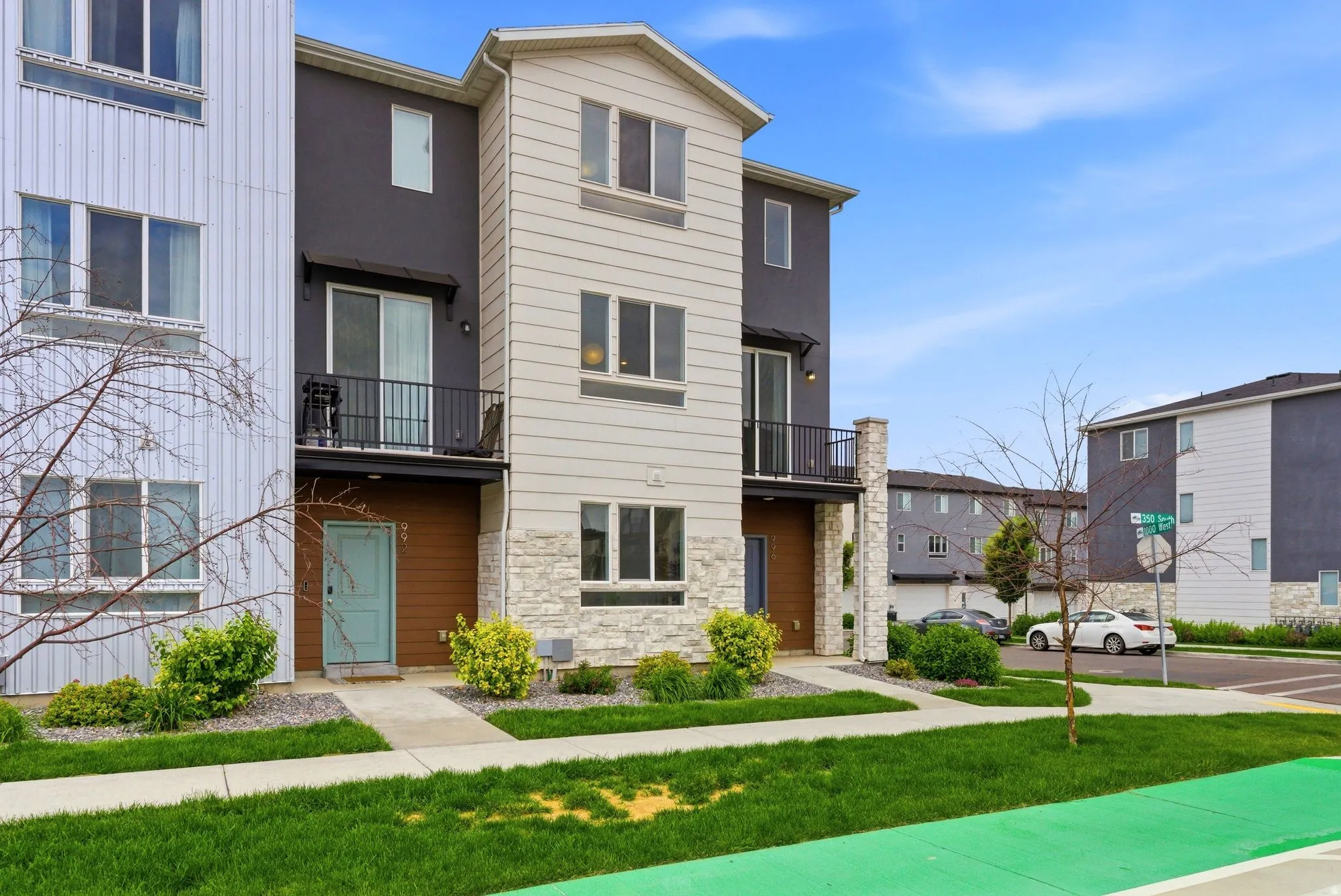 Three-story townhome featuring a light beige facade with stone accents and a contrasting dark gray section