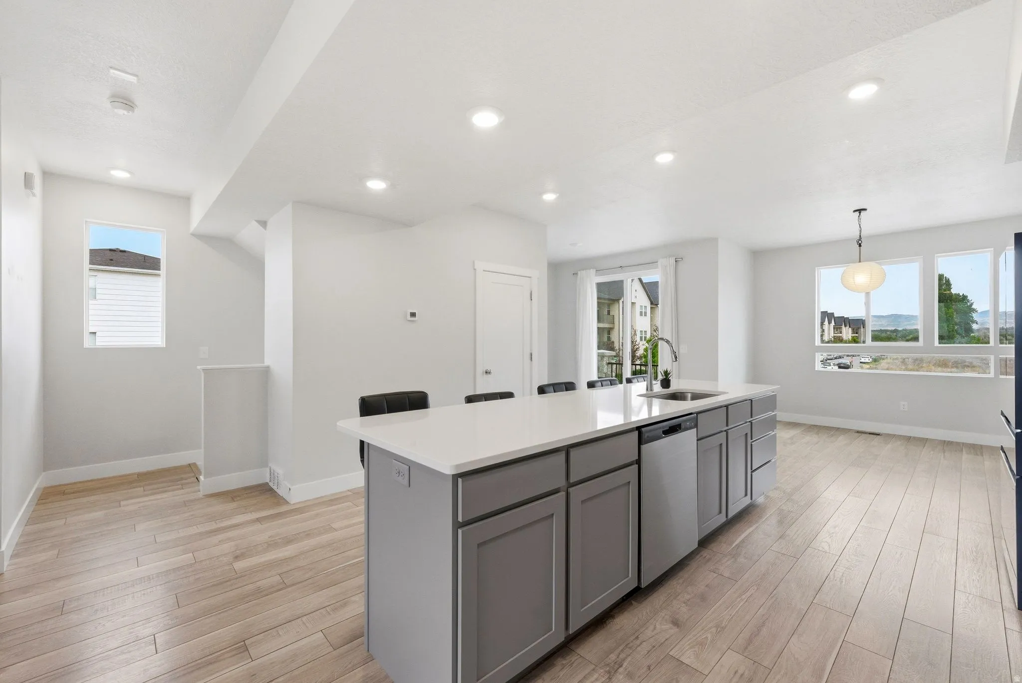 Spacious kitchen featuring a large island with light gray cabinetry, a stainless steel dishwasher, and a white countertop