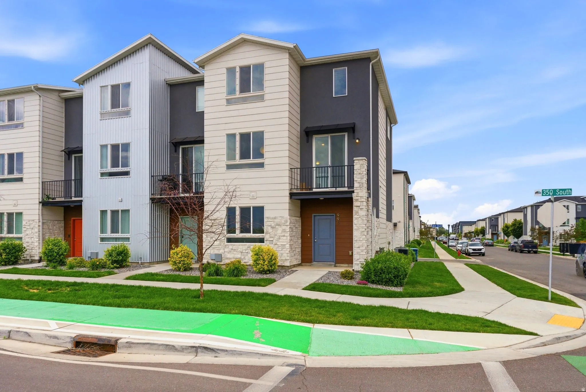 Modern multi-level townhome featuring a mixed-material facade with stone accents, dark siding, and light paneling