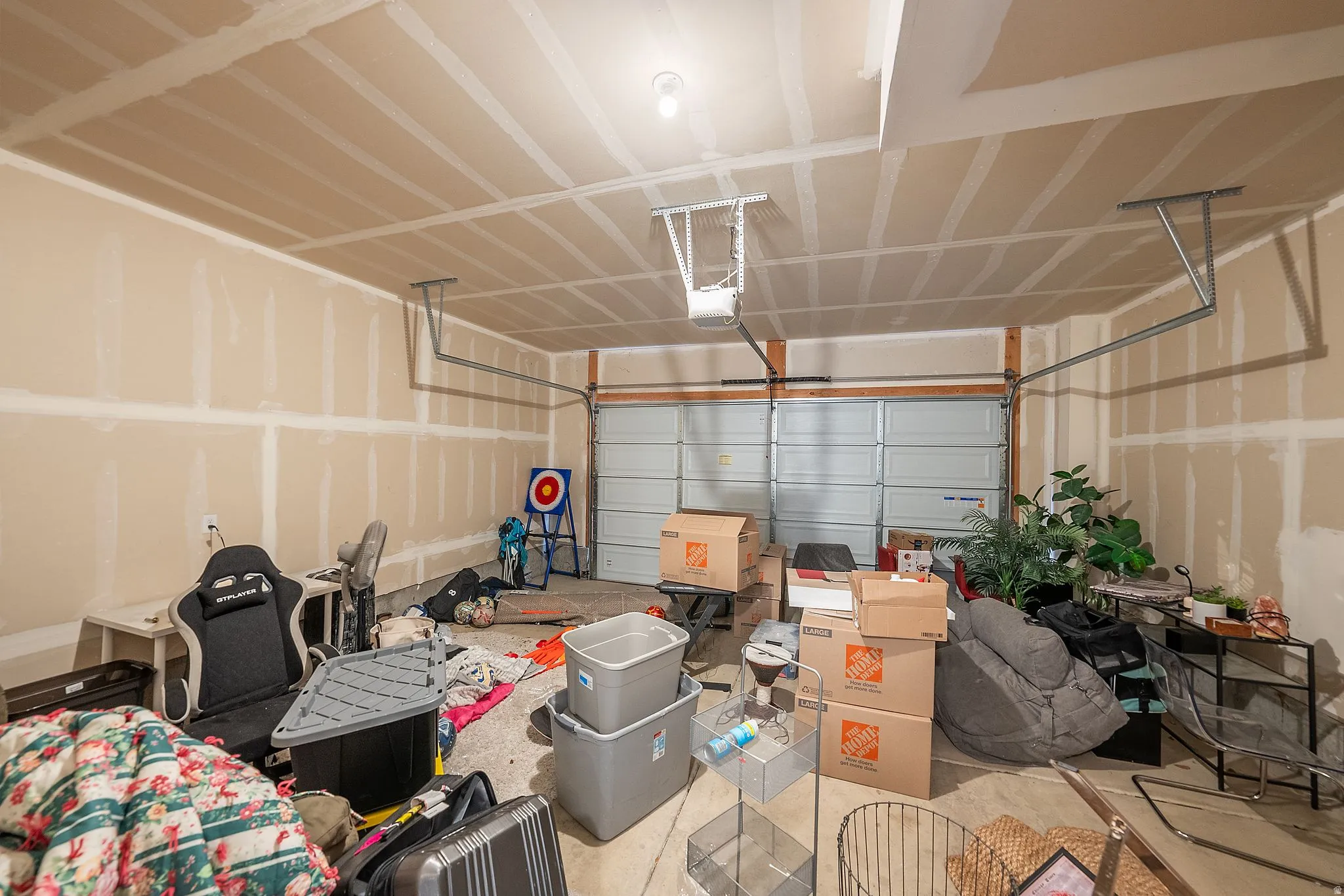 Two-car garage featuring a sectional garage door, exposed ceiling joists, and an overhead lighting fixture