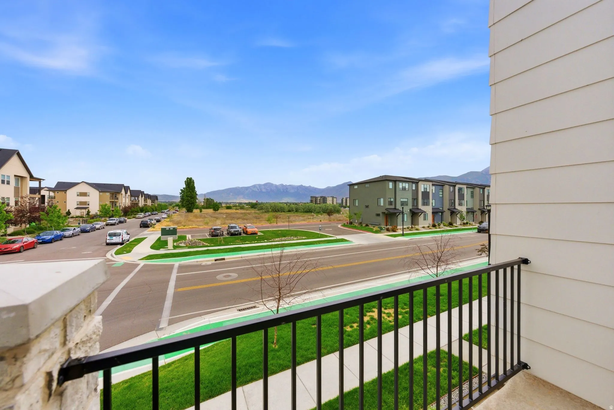 Private balcony with black wrought iron railing, concrete flooring, and stone facade accents