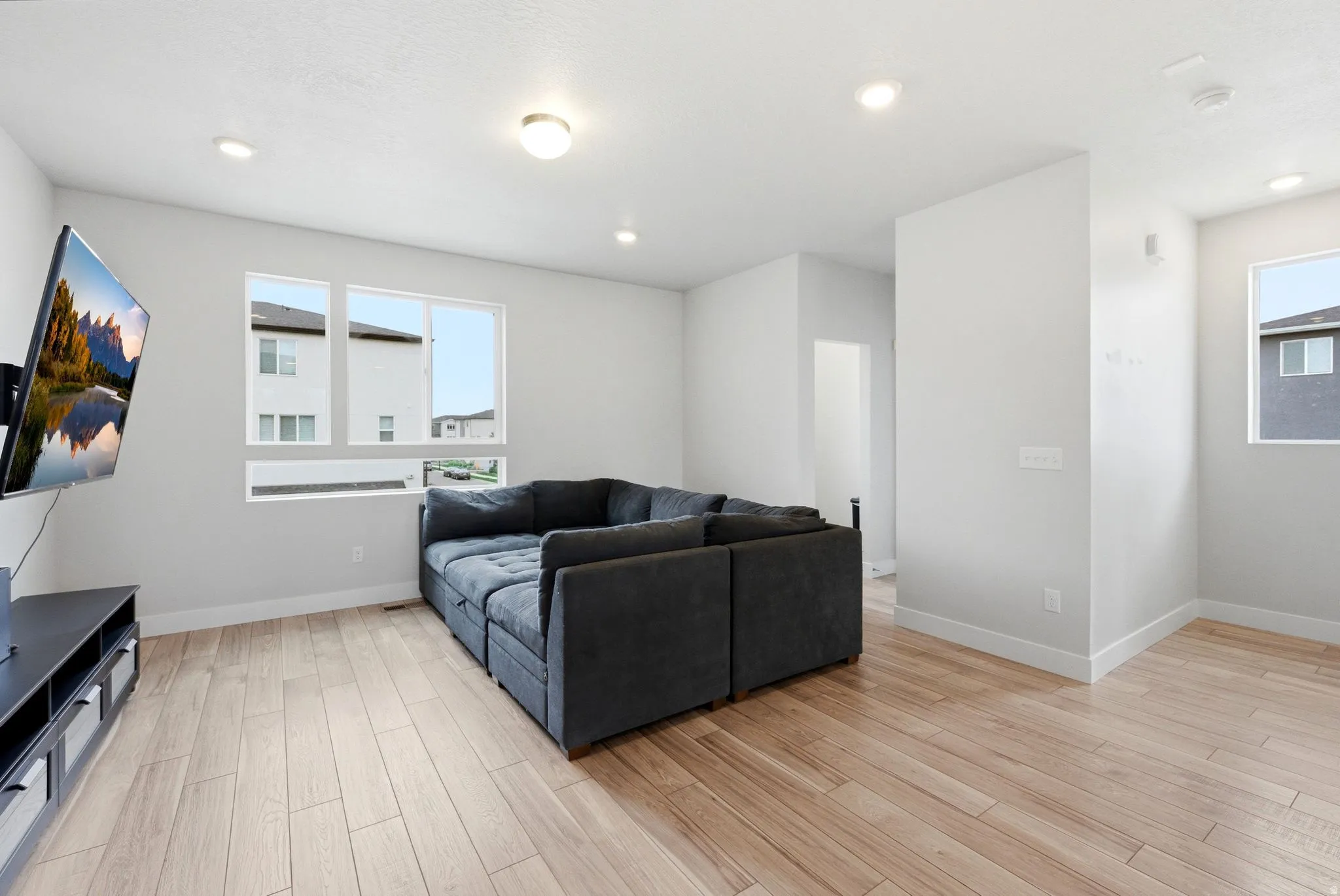 Open-concept living space featuring wood-finish flooring, recessed lighting, and large windows