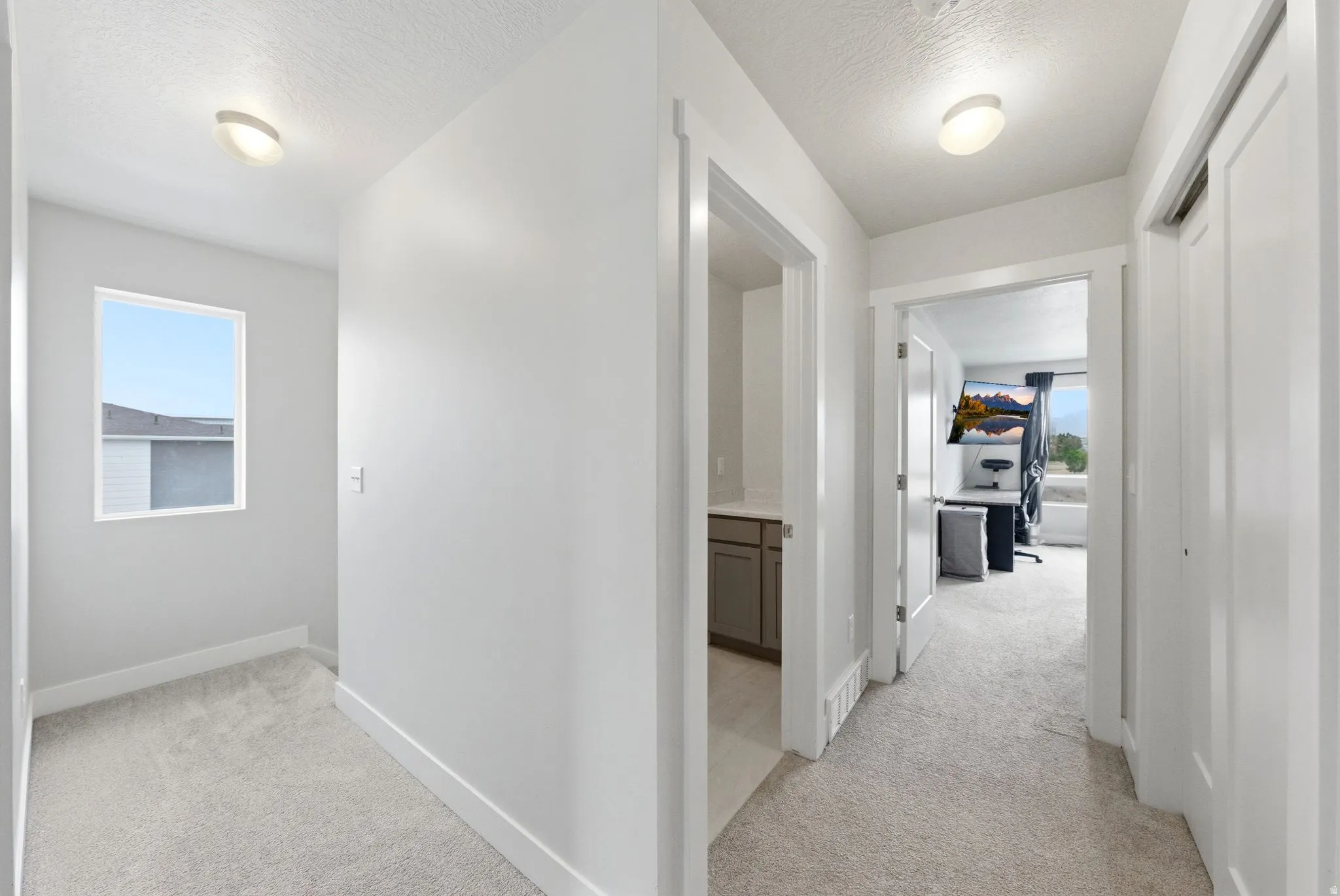 Hallway with plush carpeting, recessed ceiling lighting, and crisp white walls