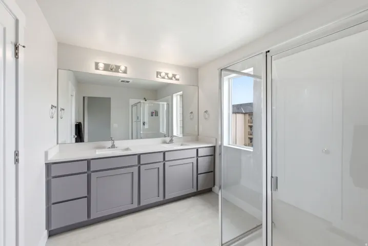 Double vanity featuring gray shaker-style cabinetry, white countertops, and dual undermount sinks with chrome fixtures