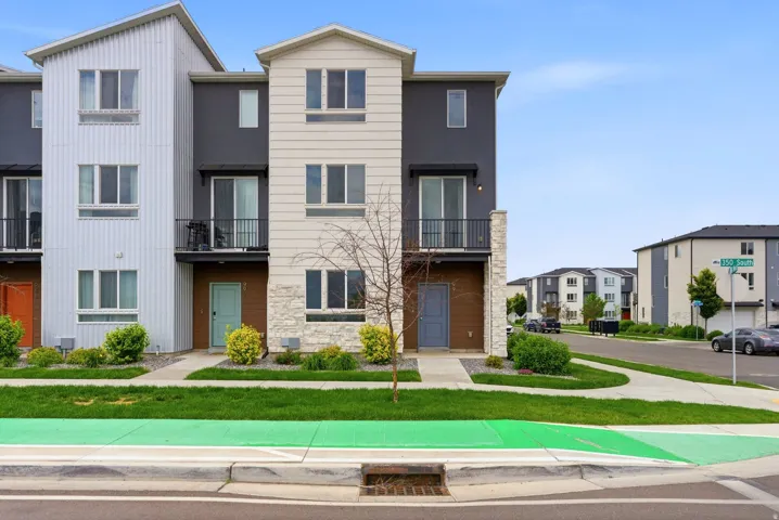 Contemporary townhome exterior featuring multi-toned siding, stone accents, and multiple balconies