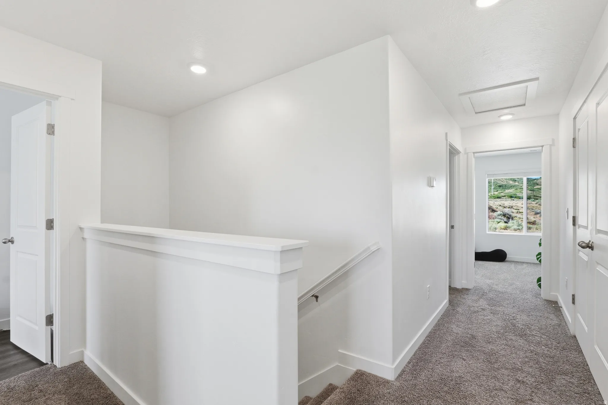Upper landing with plush gray carpeting and recessed lighting