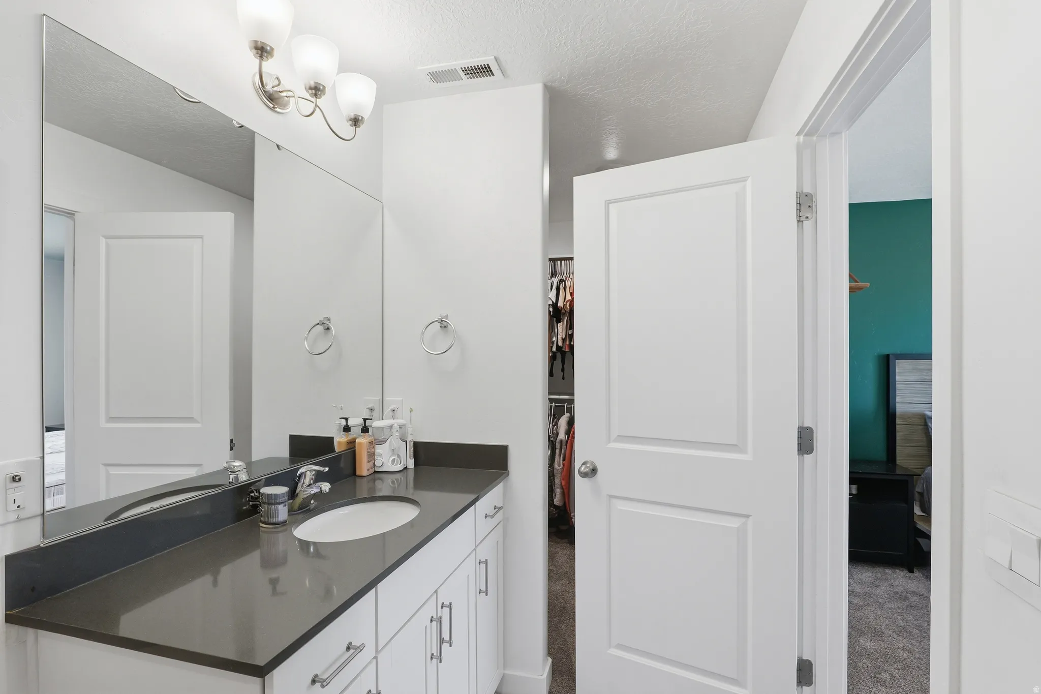 Bathroom featuring a single vanity with a gray countertop, white cabinetry, and brushed nickel hardware