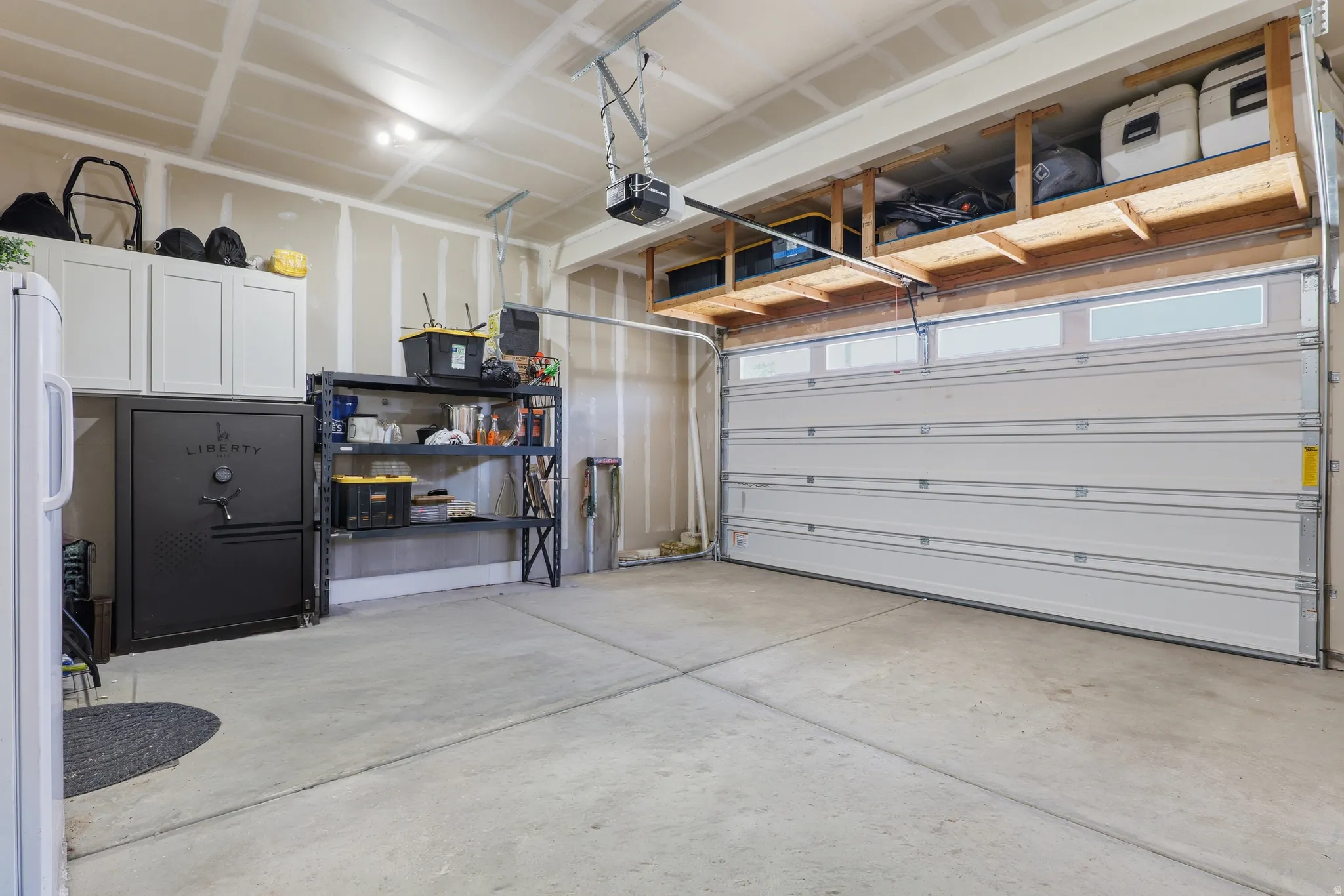 Spacious garage featuring a sectional garage door with upper windows, concrete flooring, and an automatic garage door opener