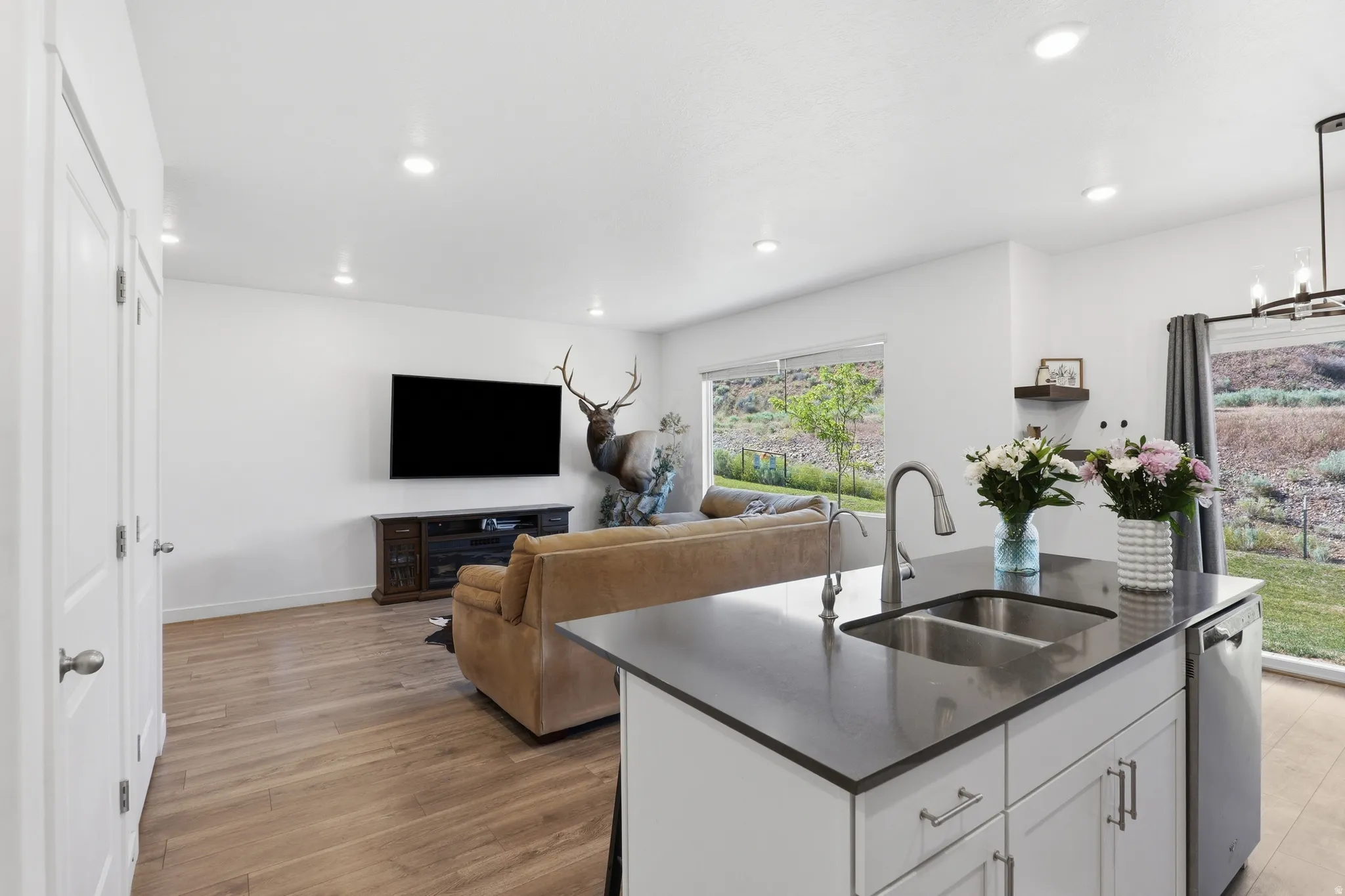 Kitchen island featuring a double basin stainless steel sink, a gooseneck faucet, and a built-in dishwasher
