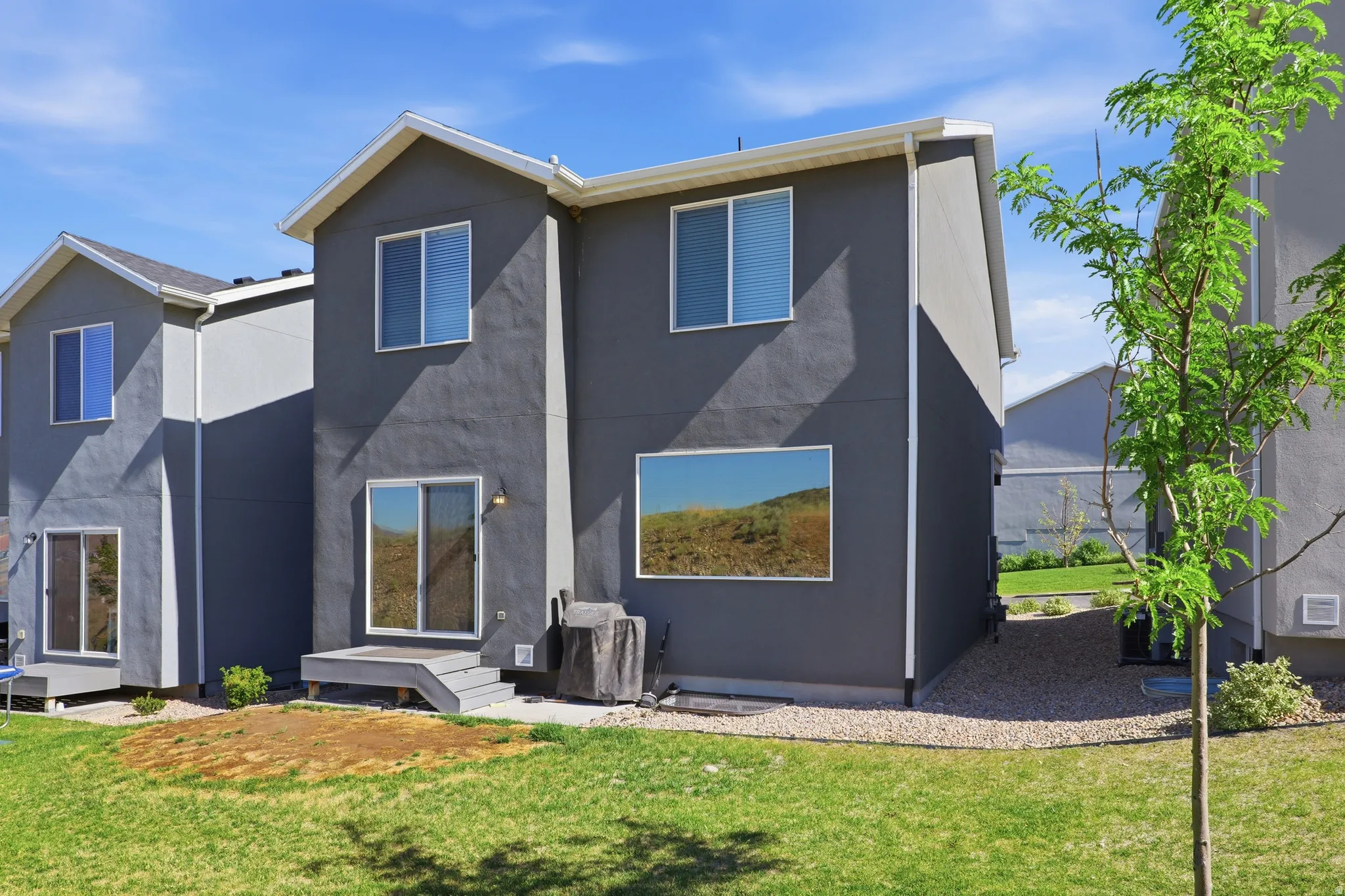 Rear exterior showcasing dark gray stucco siding, white trim, and a gabled roofline