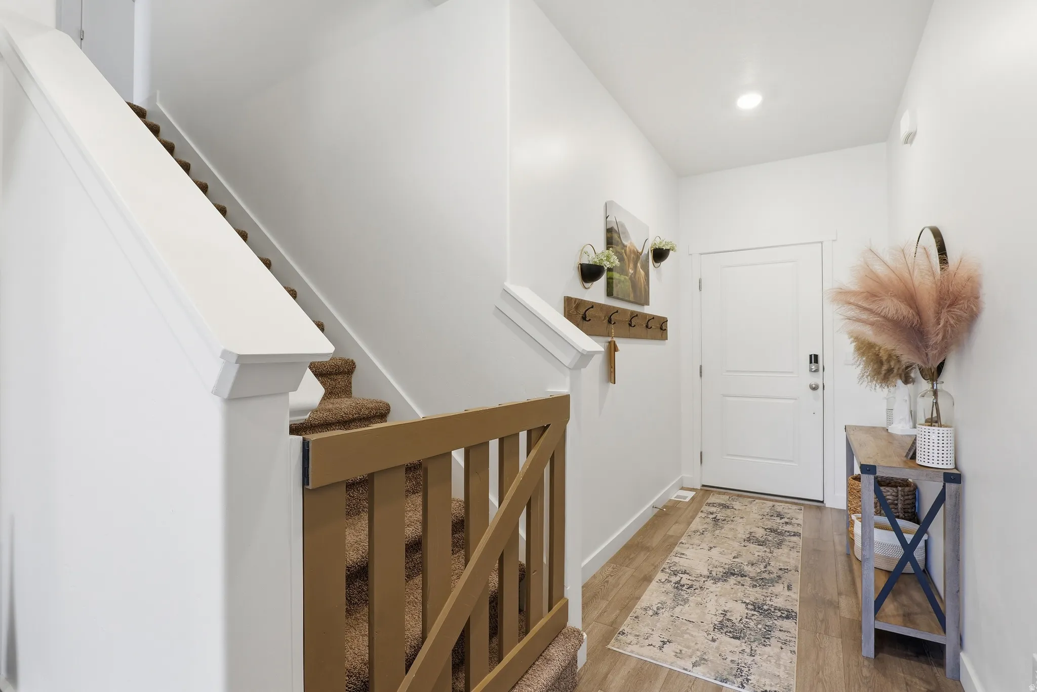 Foyer featuring wood-finish flooring, white walls, recessed lighting, and a white entry door