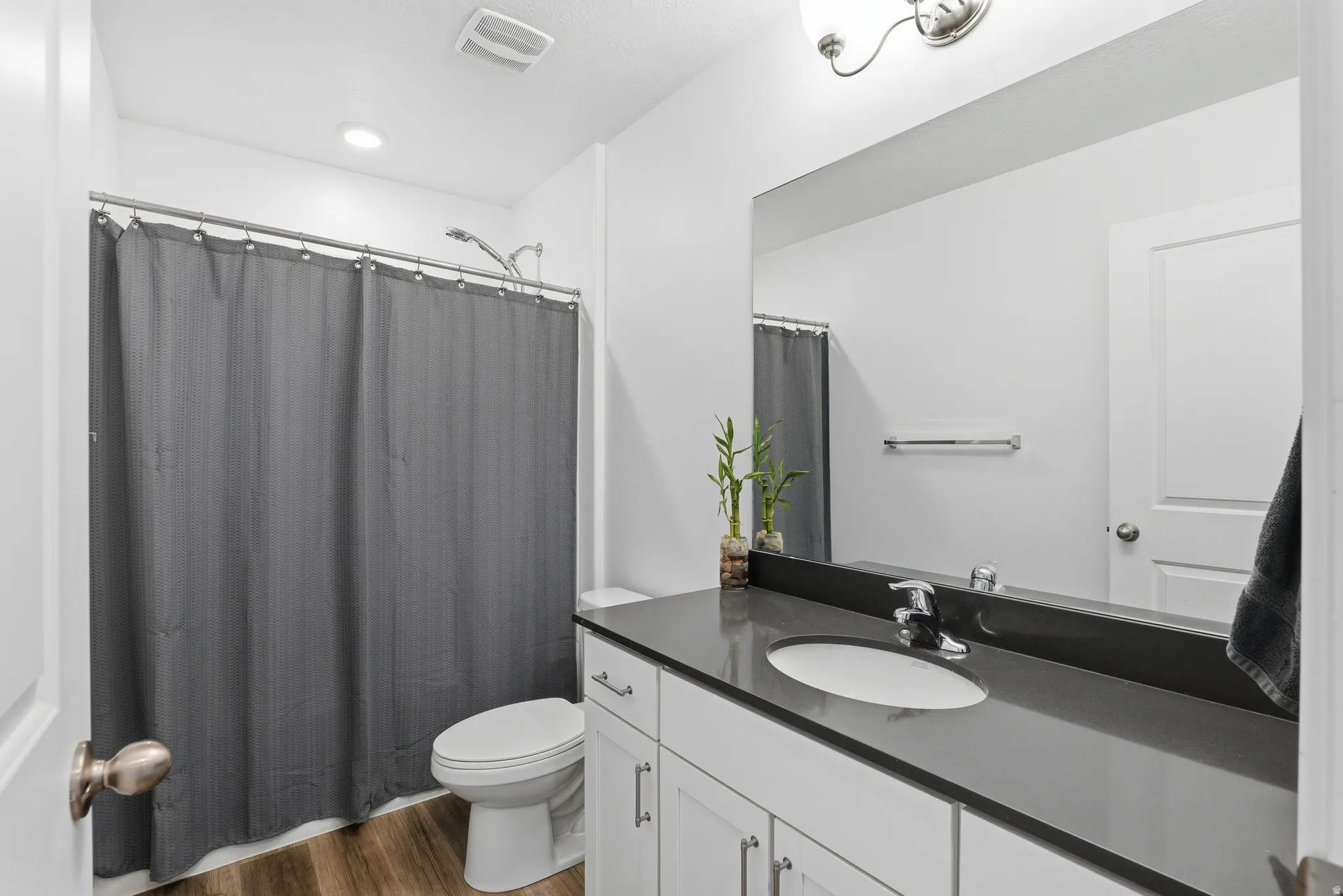 Bathroom featuring a white vanity with a dark countertop, an undermount sink, and a chrome faucet