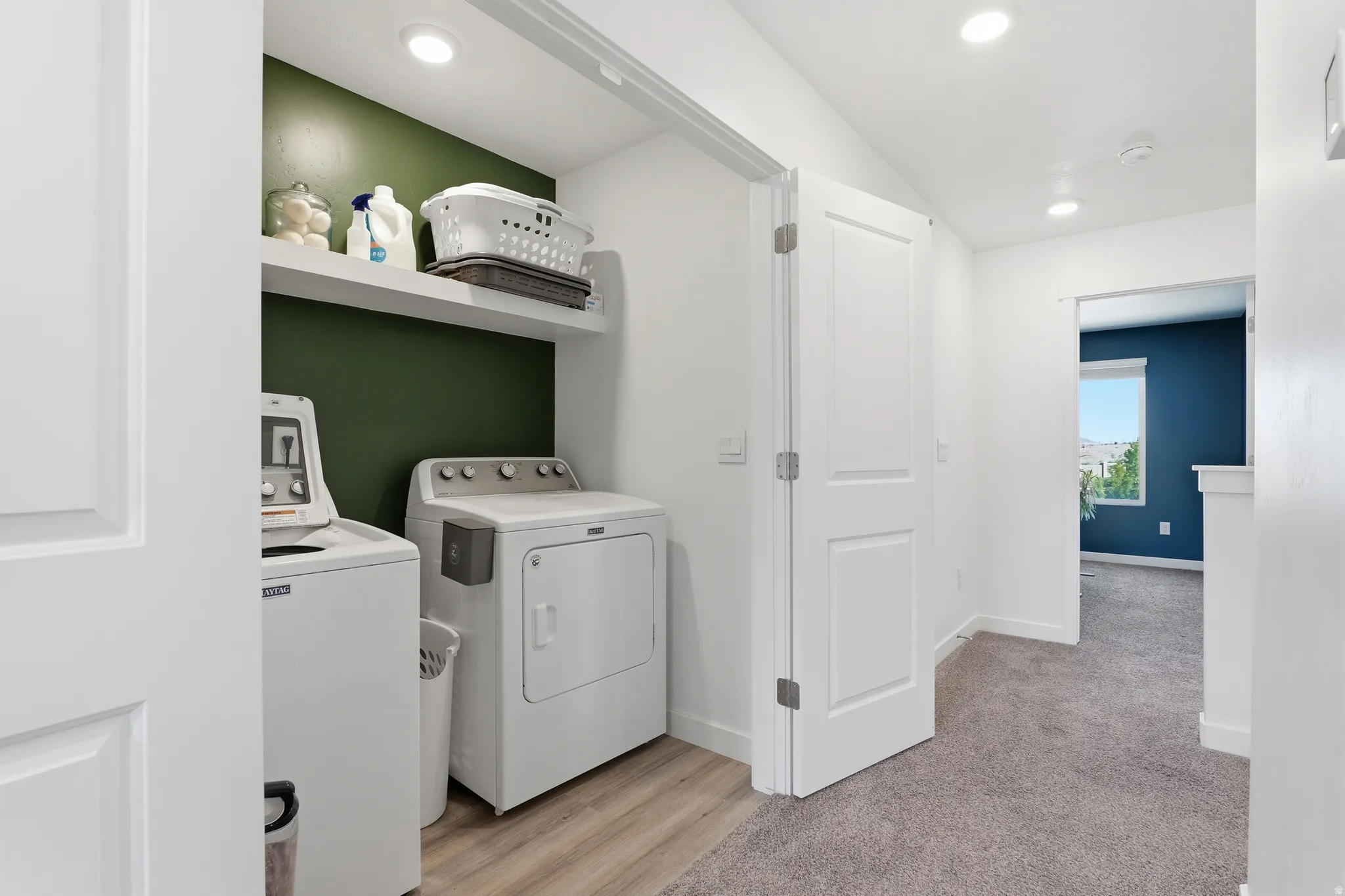 Dedicated laundry area featuring a white floating shelf, recessed lighting, and a contrasting accent wall