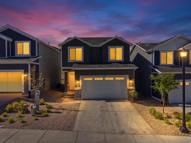 Contemporary two-story residence featuring a dark siding exterior with stone accents and a two-car garage