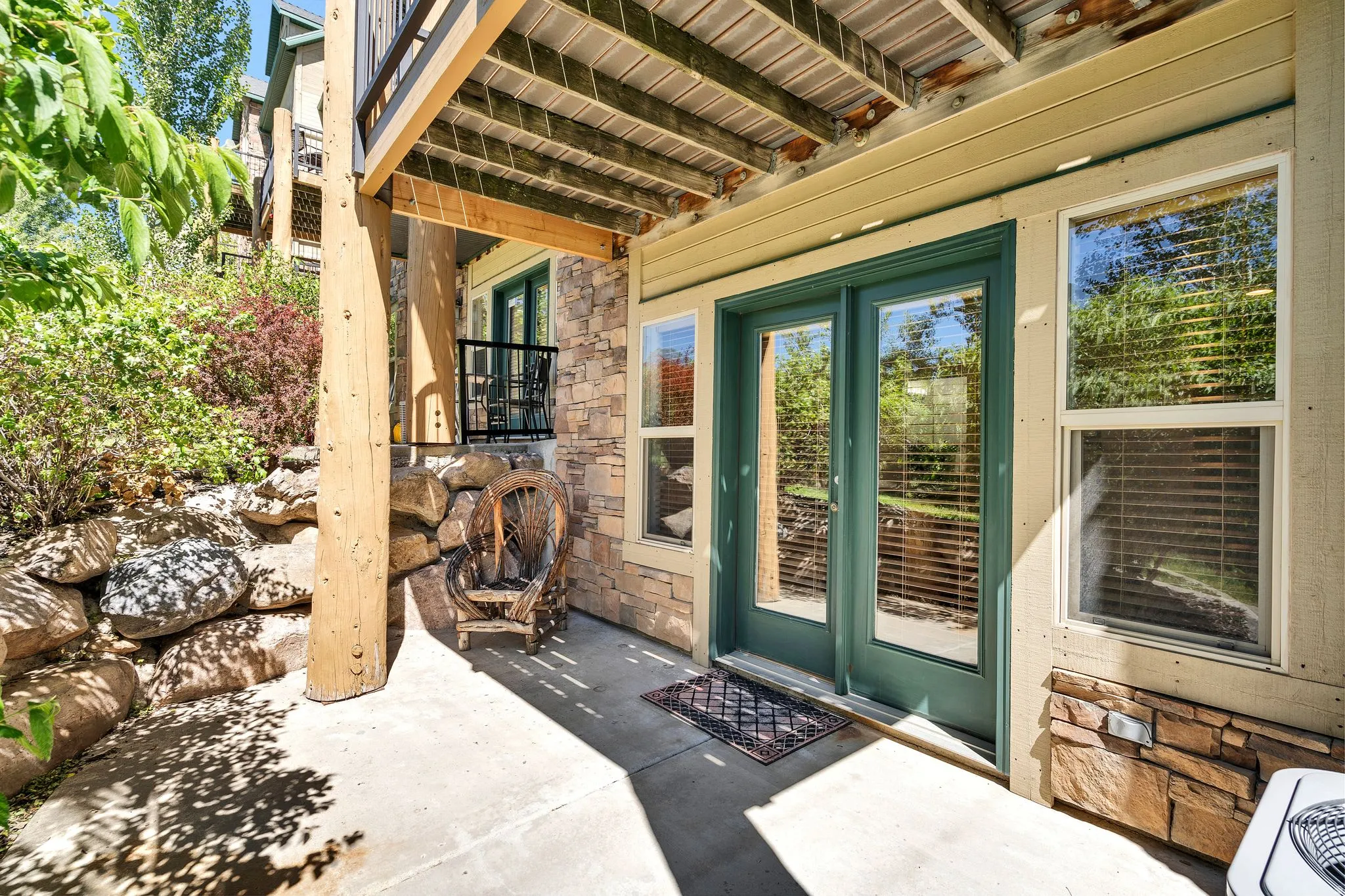 Outdoor patio with concrete flooring, stone veneer siding, and a wooden support beam