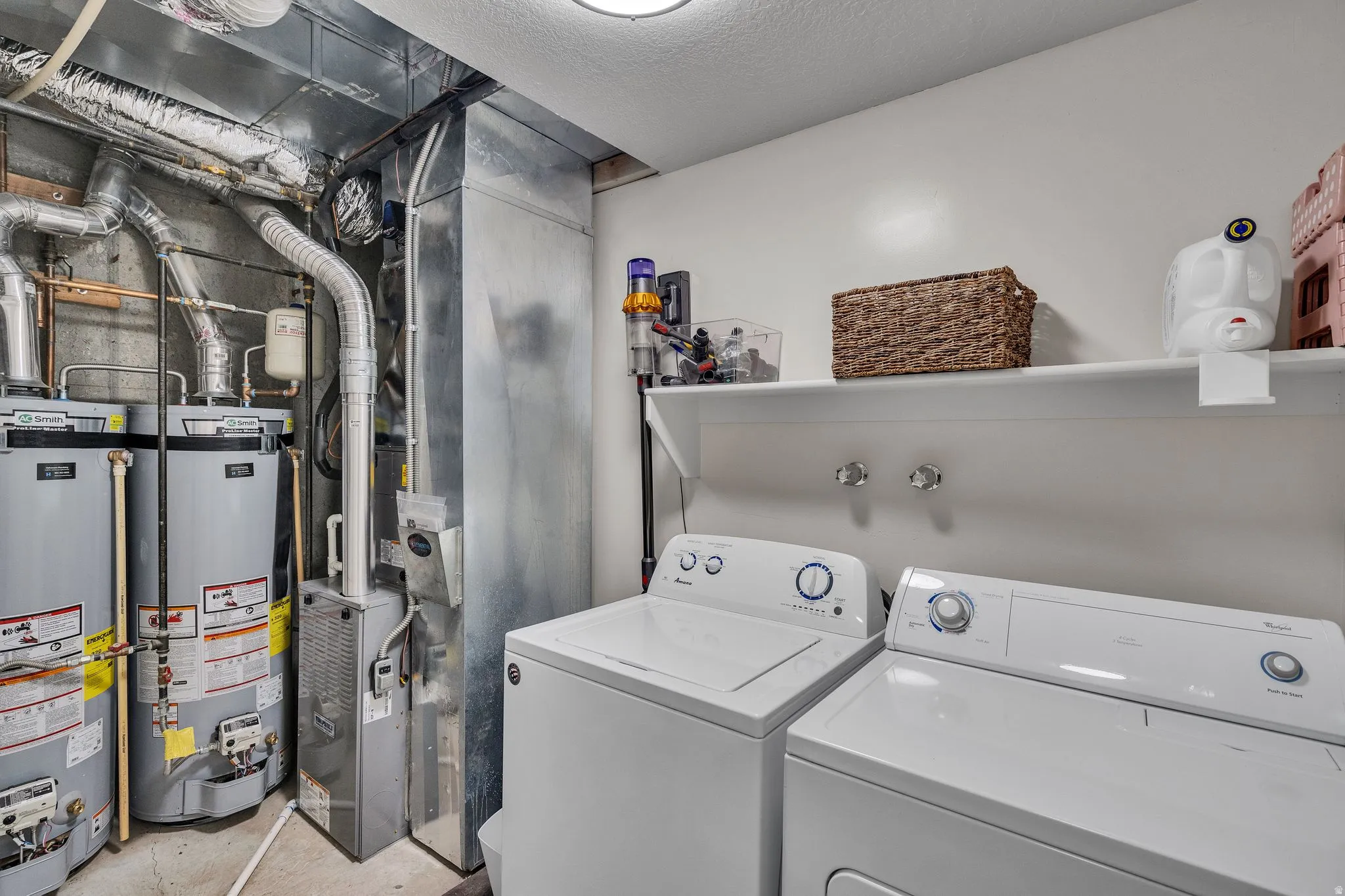 Dedicated utility area featuring a top-load washing machine, front-load dryer, and wall-mounted shelving
