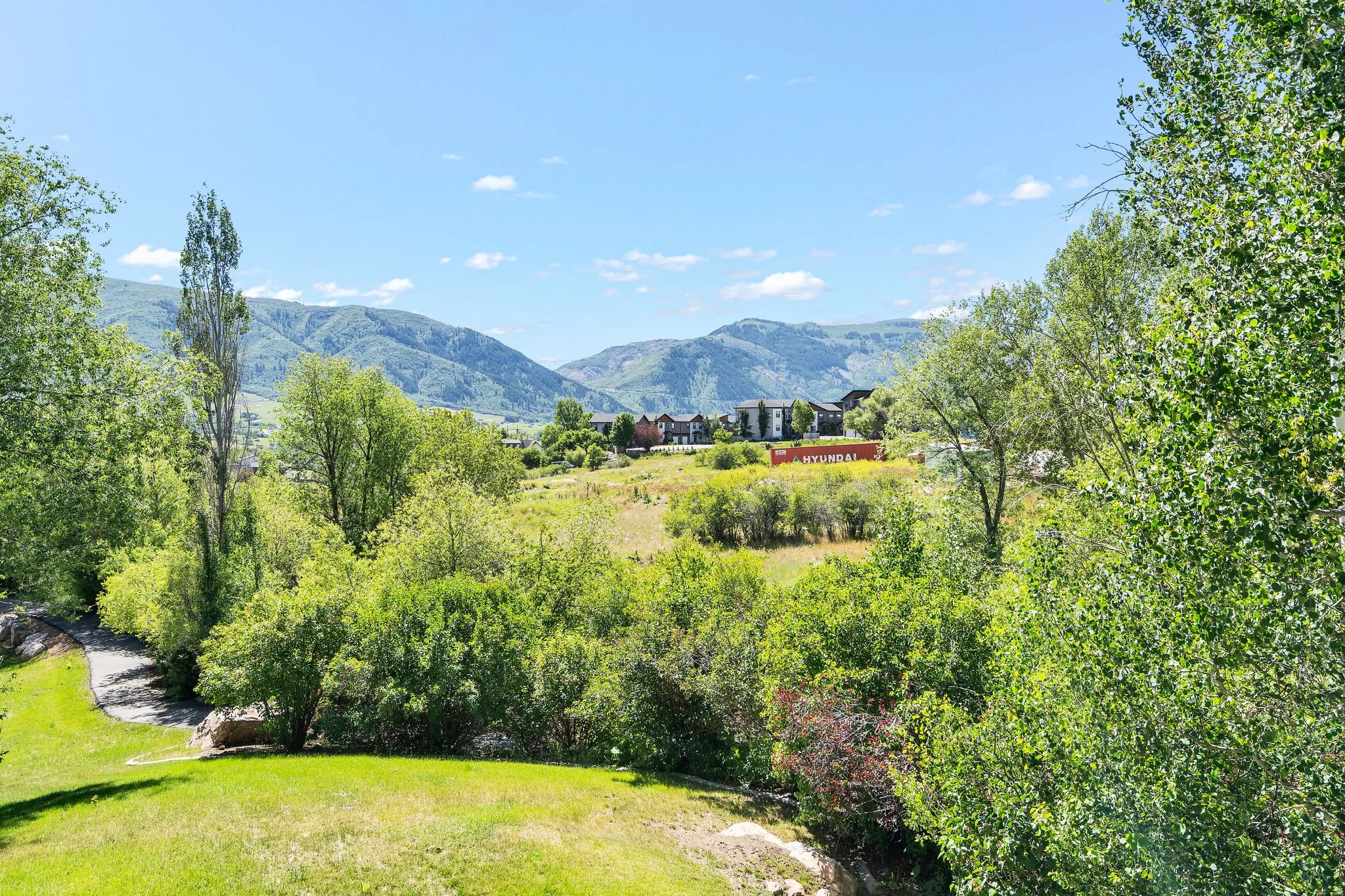 Expansive outdoor grounds featuring a rolling lawn and mature trees, surrounded by distant mountains