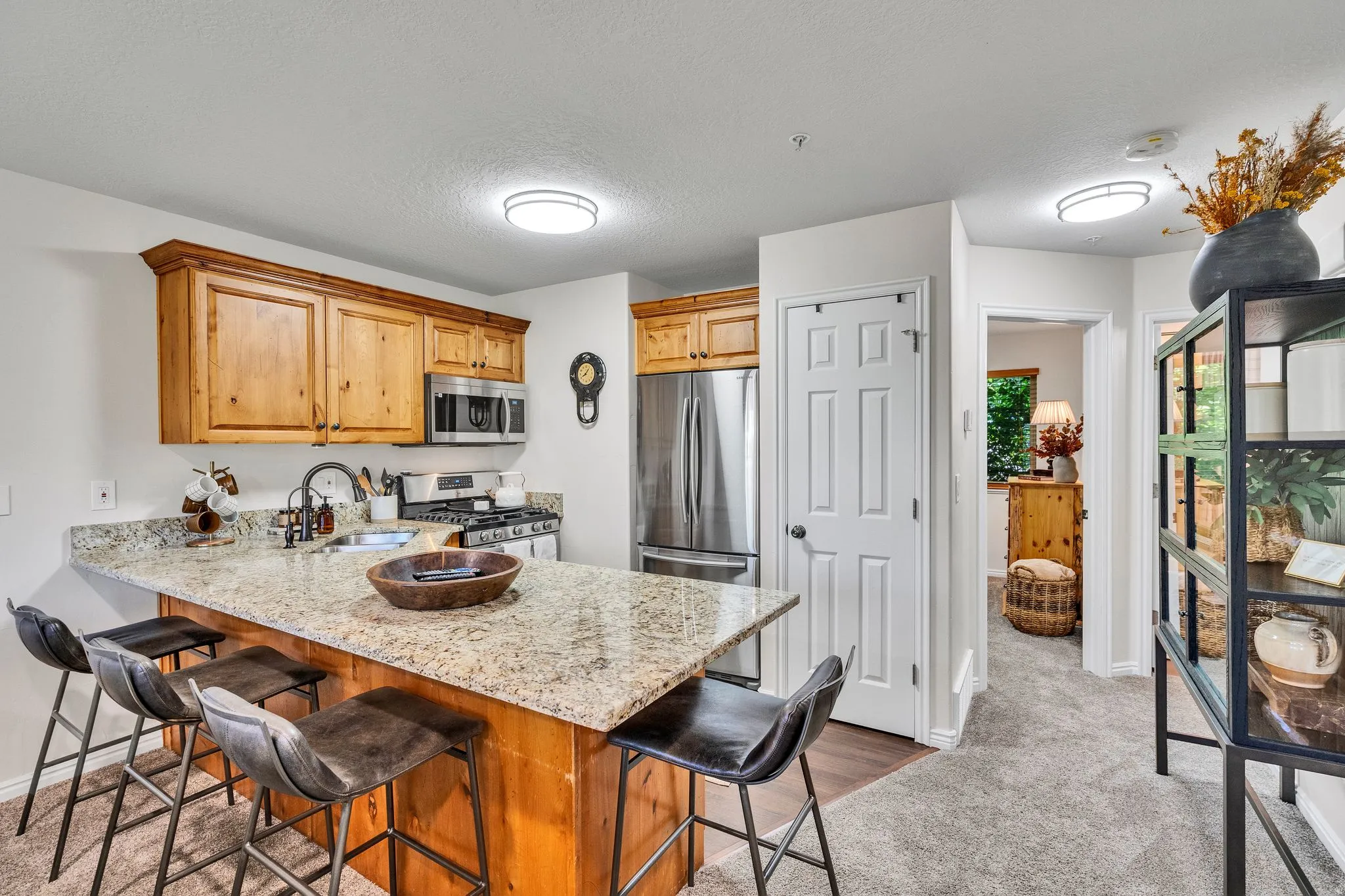 Kitchen with granite-style countertops, wood cabinetry, stainless steel appliances, and a breakfast bar