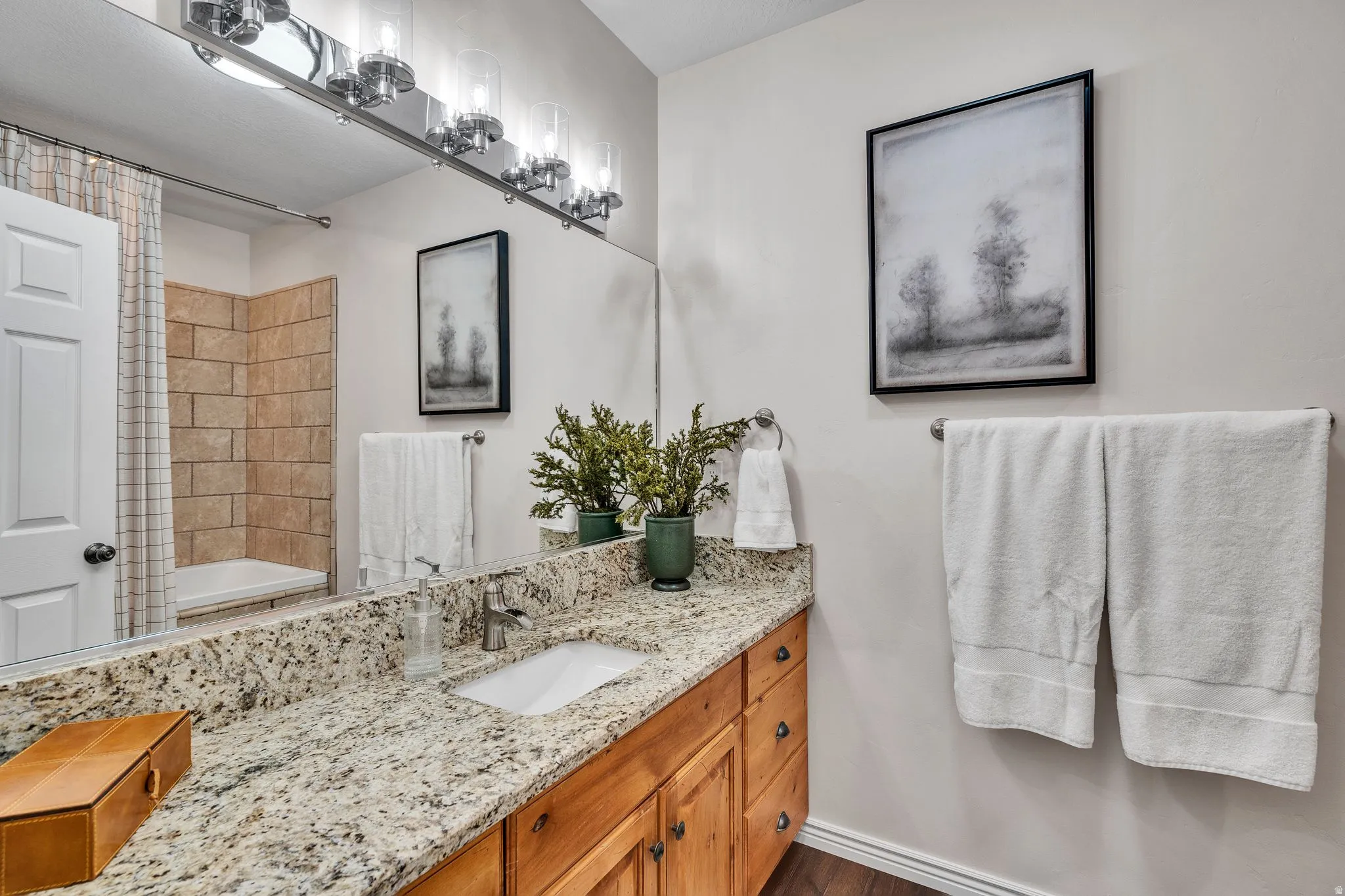 Bathroom featuring a vanity with a light-colored granite countertop, an undermount sink, and wood-finish cabinetry