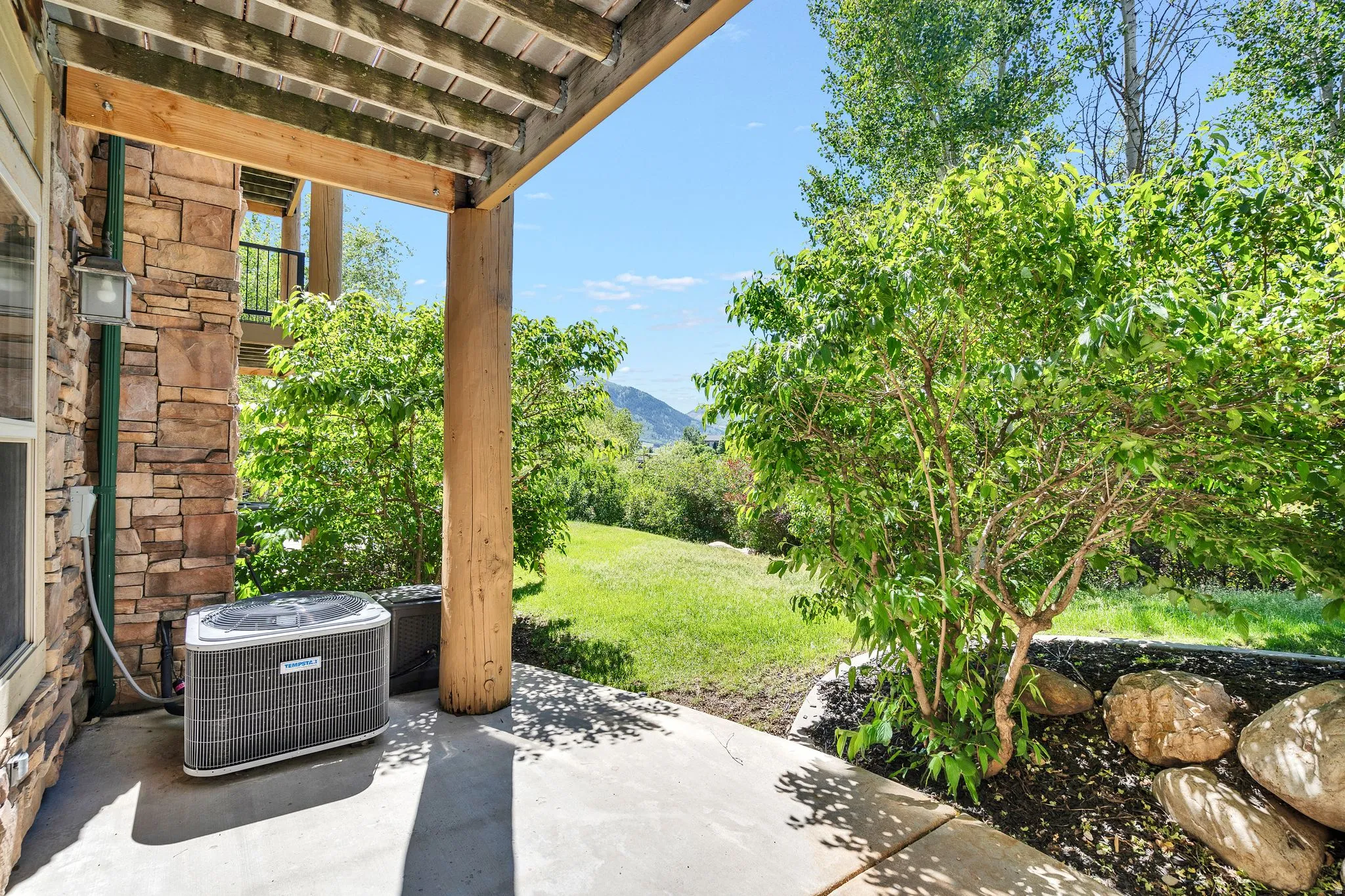 Covered patio featuring a stacked stone exterior and wooden support beams