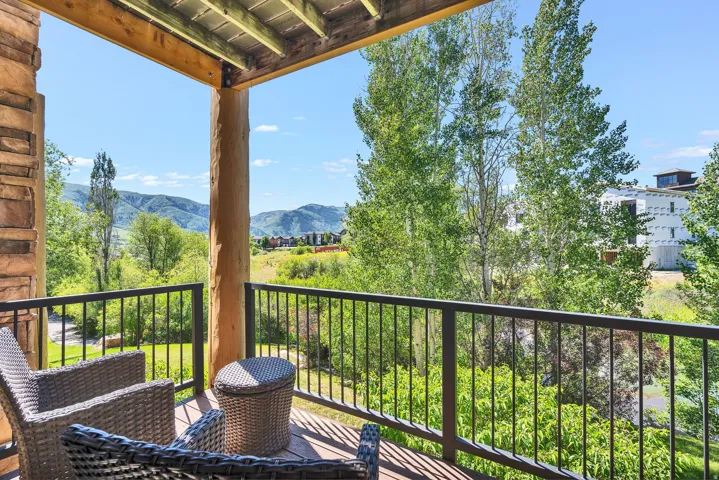 Balcony featuring a wood-finish deck, robust log column, and a stone-clad wall