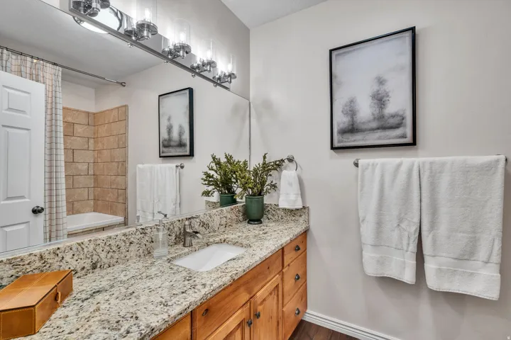Bathroom featuring a vanity with a light-colored granite countertop, an undermount sink, and wood-finish cabinetry