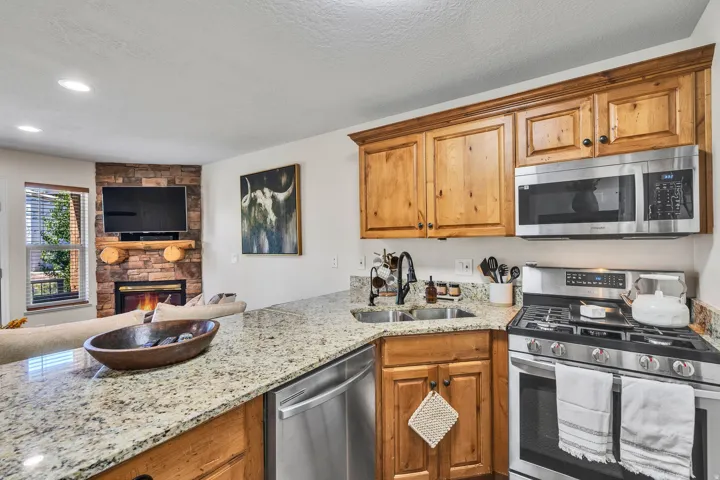 Kitchen featuring granite countertops, stainless steel appliances, custom wood cabinetry, and a double basin sink with a modern faucet
