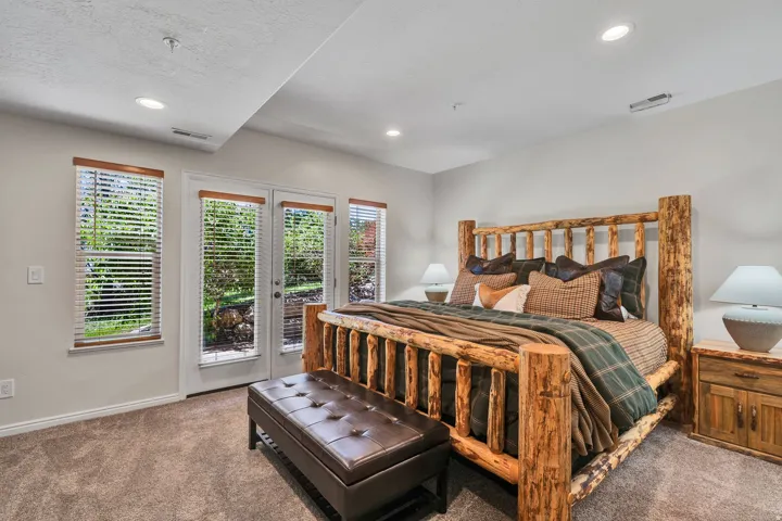 Recessed lighting illuminates a carpeted room featuring a double door exterior entry, two vertical windows with blinds, and light gray walls