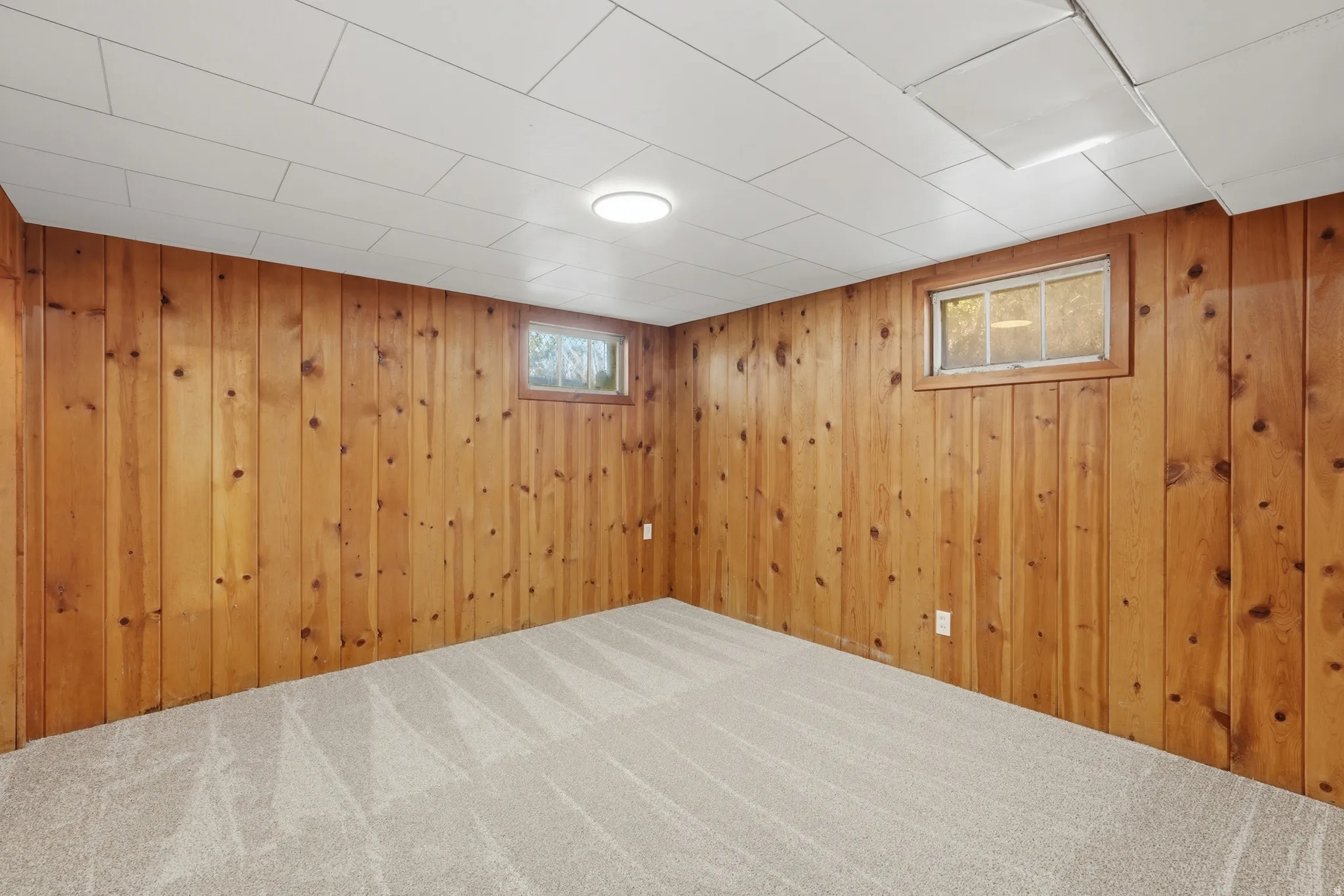 Room featuring wood paneling, light gray carpeting, and a white paneled ceiling with recessed lighting