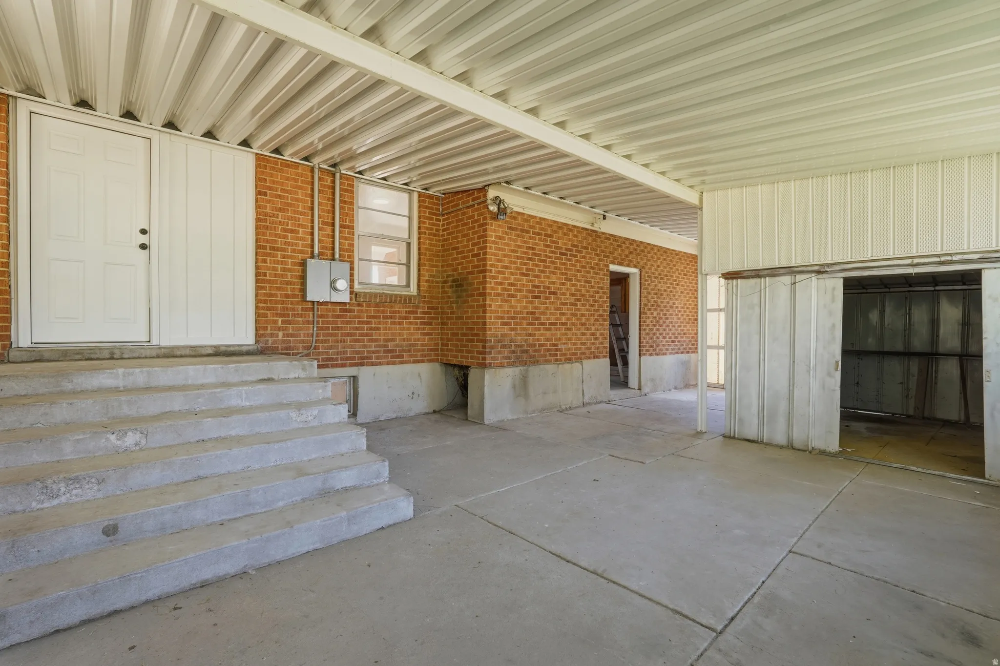Covered concrete patio featuring a corrugated metal ceiling