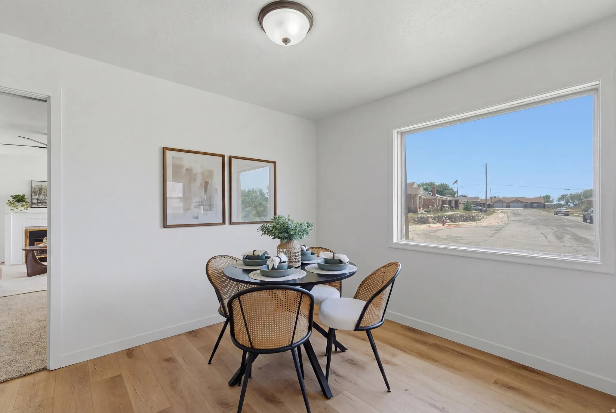 Dining area featuring wood-finish flooring, white baseboards, a large picture window, and a ceiling-mounted light fixture