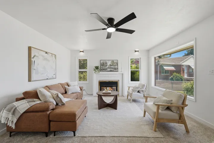 Living area featuring a fireplace with a white mantel, ceiling fan, recessed lighting, and large picture windows