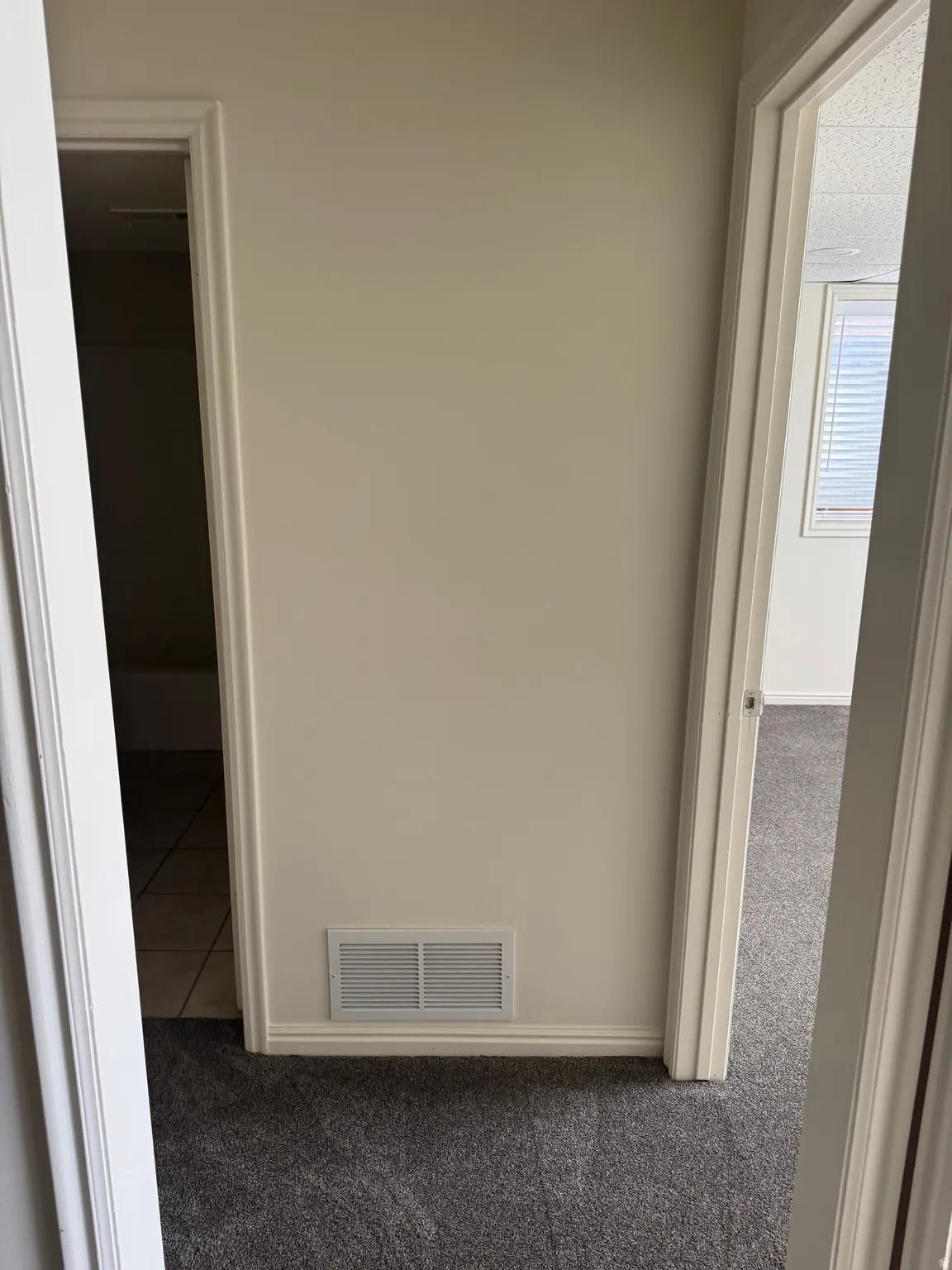 Wall with baseboard trim and a floor-level vent, flanked by two doorways