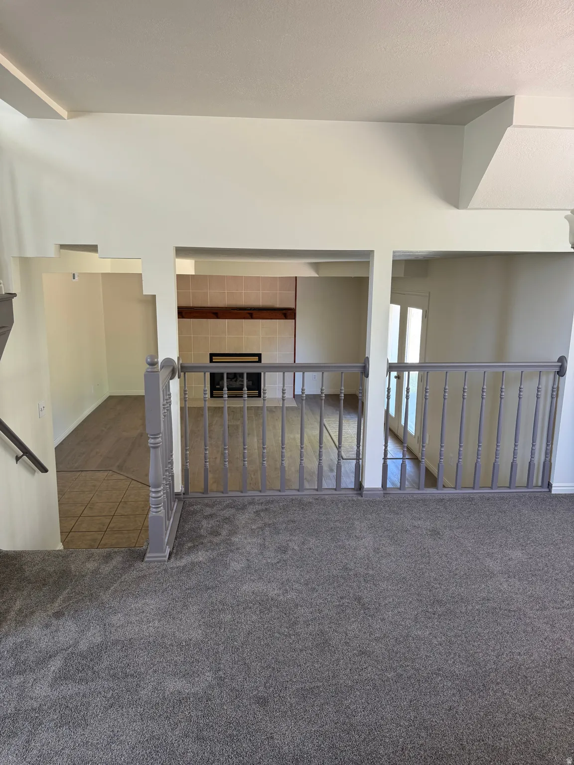 Multi-level interior featuring a gray carpeted upper level and wood-finish flooring below