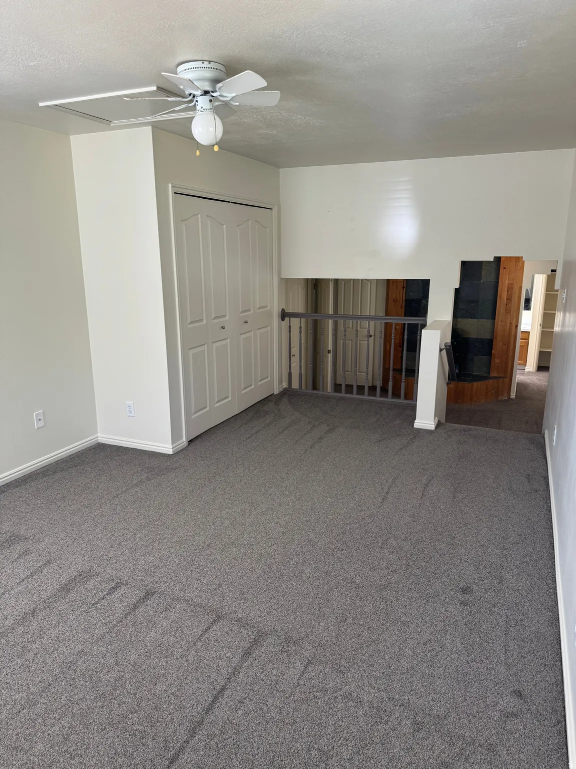 Carpeted room featuring a ceiling fan with light, bi-fold closet doors, and painted baseboards