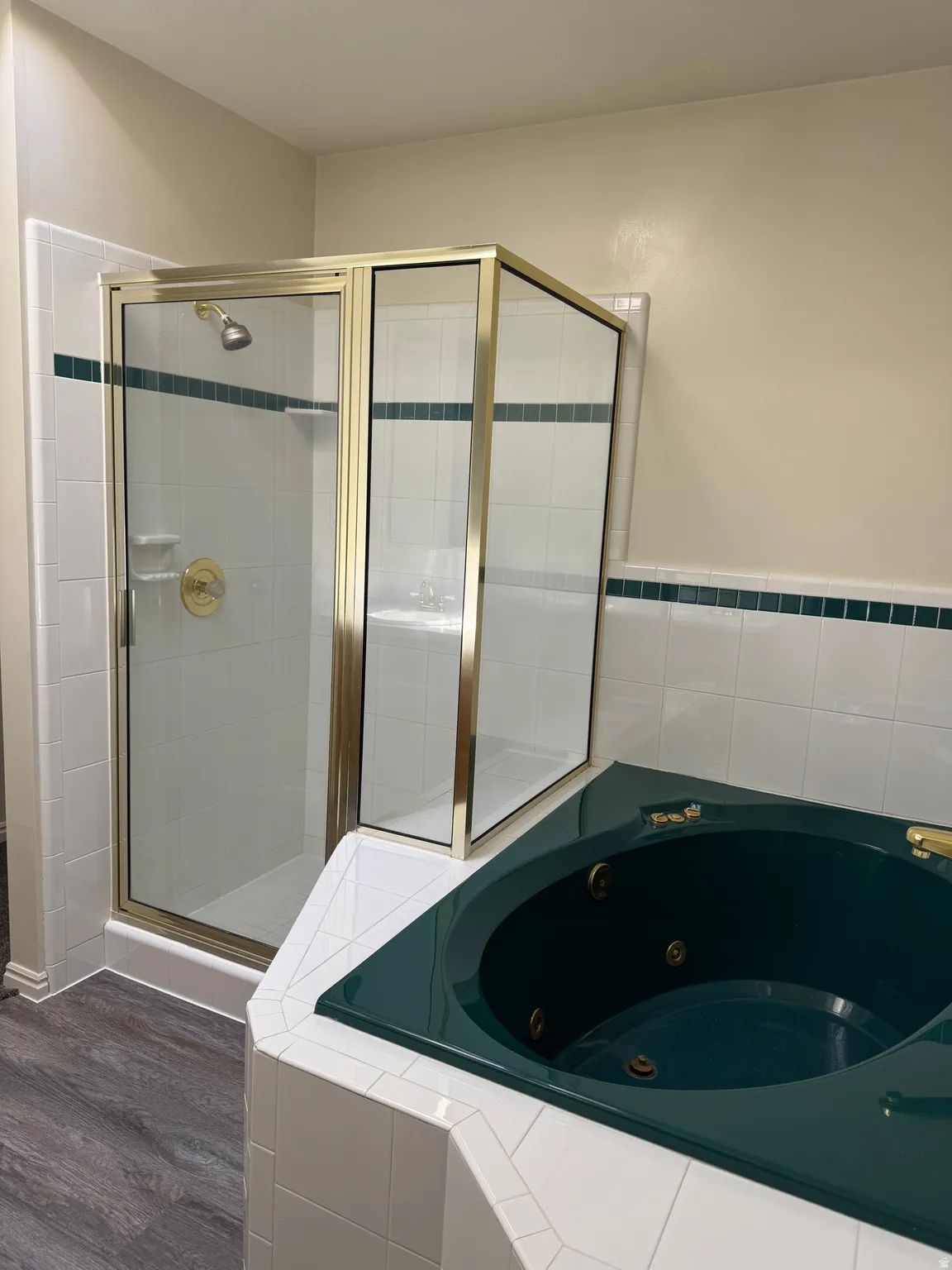 Corner soaking tub and a glass-enclosed shower with gold-tone fixtures