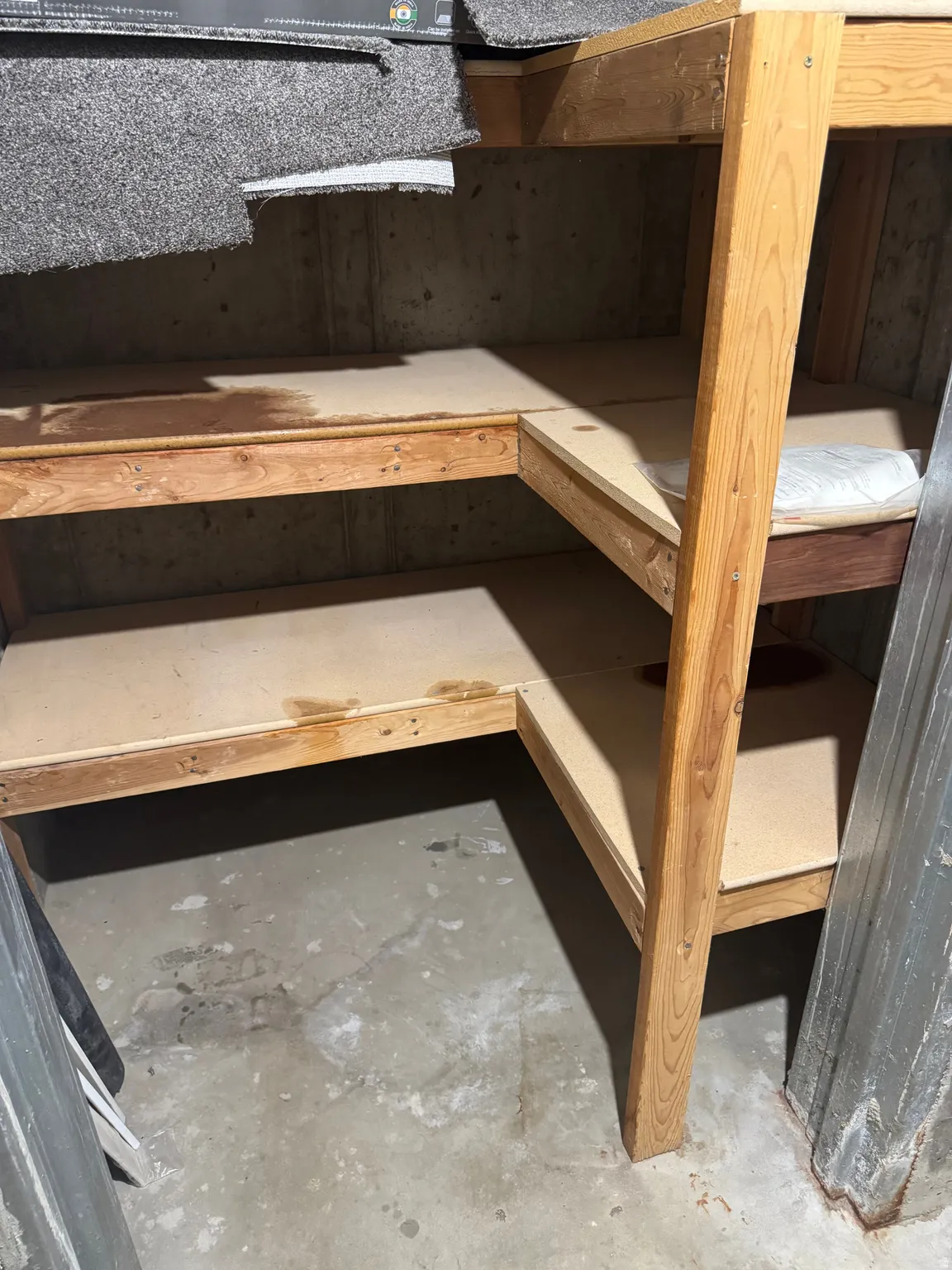 Custom-built wood shelving providing storage capacity, complemented by a concrete floor and a concrete wall