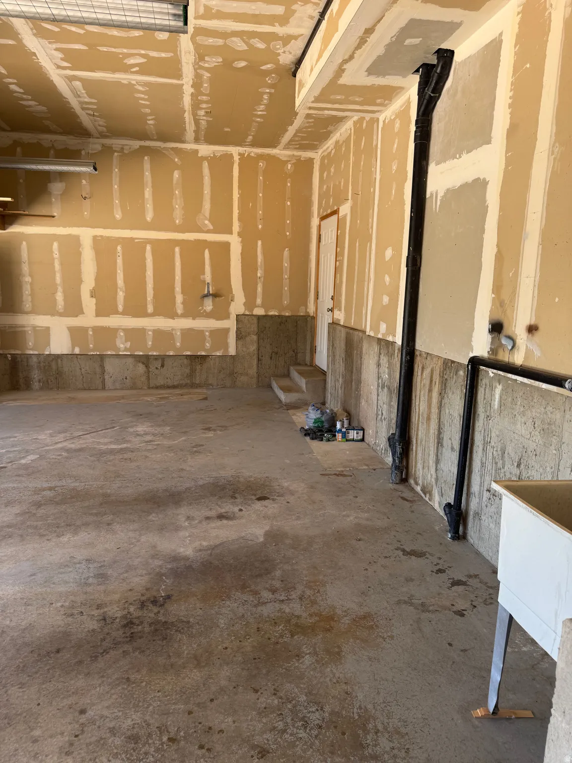 Unfinished garage interior with concrete flooring and exposed drywall