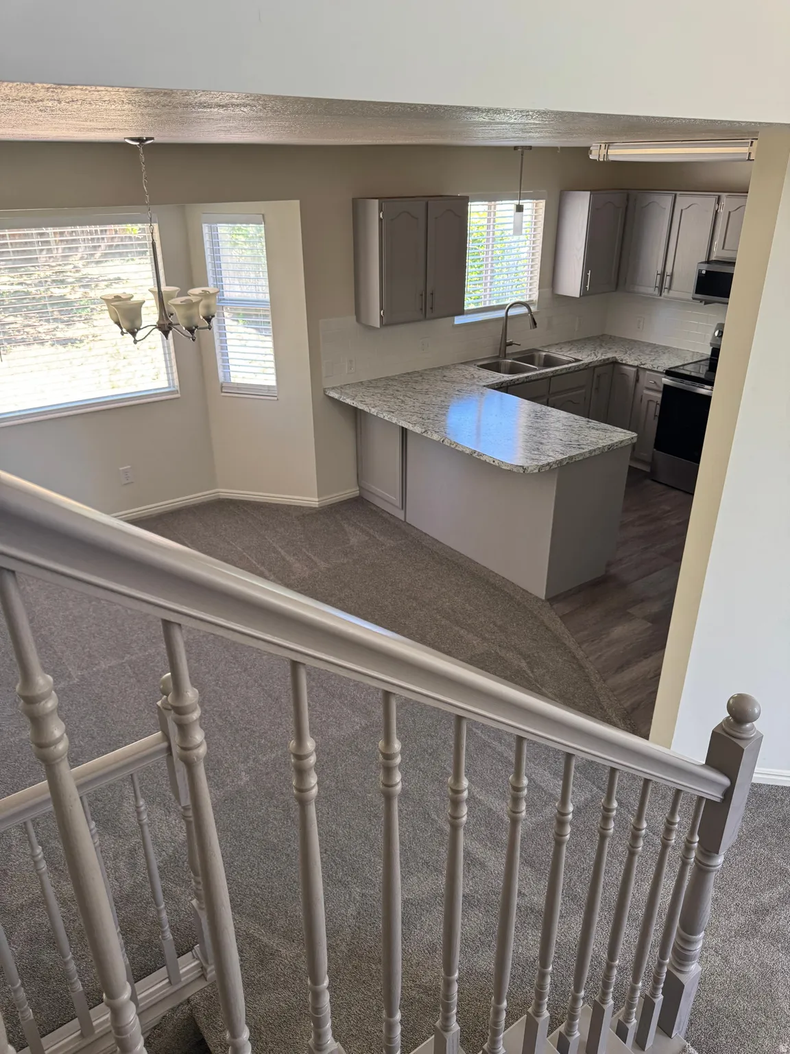 Kitchen featuring light gray cabinetry, light-toned granite countertops, a stainless steel sink with a gooseneck faucet, and a white tile backsplash