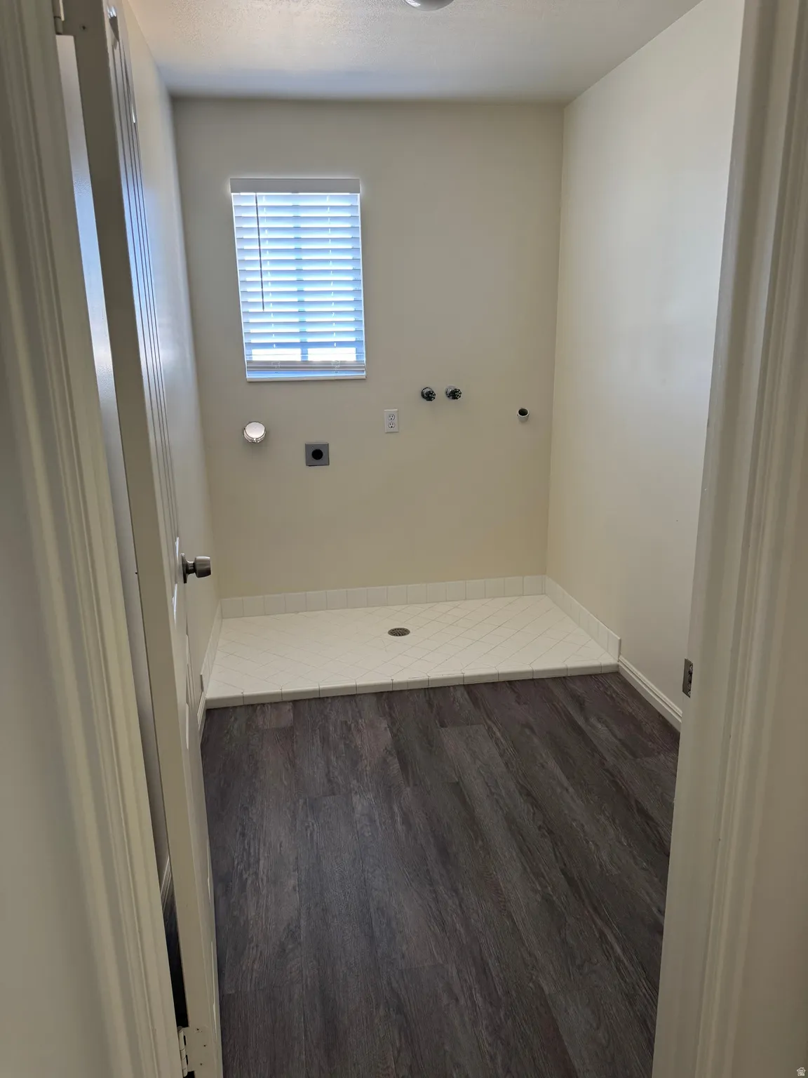 Laundry area featuring wood-finish flooring and a tiled utility pan