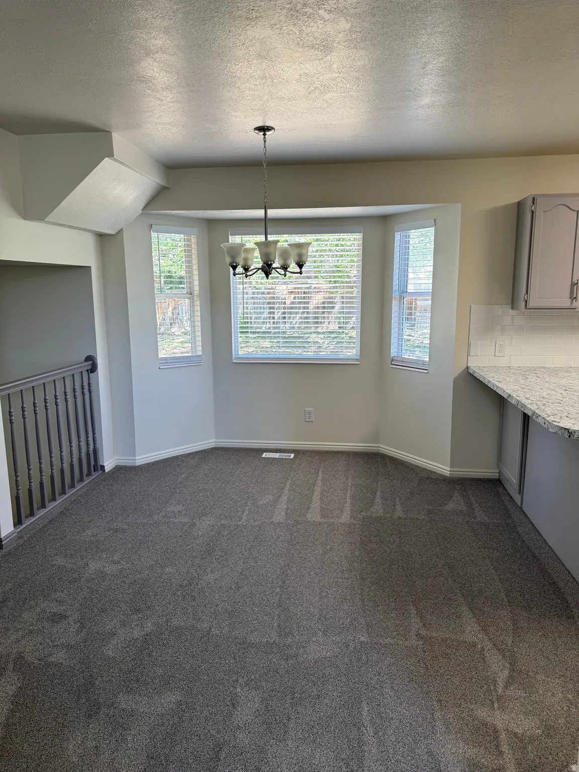 Dining area featuring a bay window, chandelier lighting, and gray carpet flooring