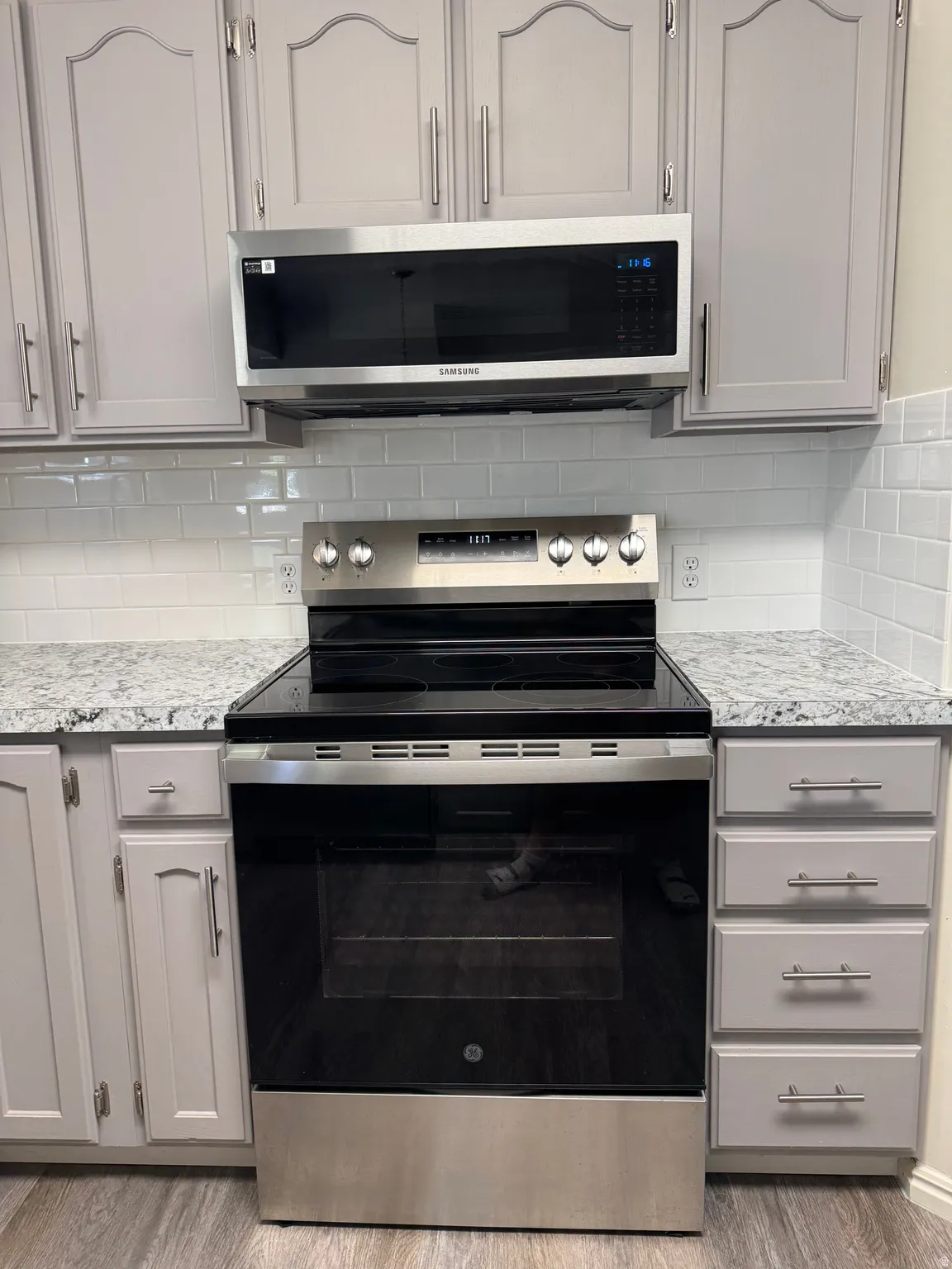 Kitchen featuring stainless steel appliances, light gray cabinetry, and a white subway tile backsplash