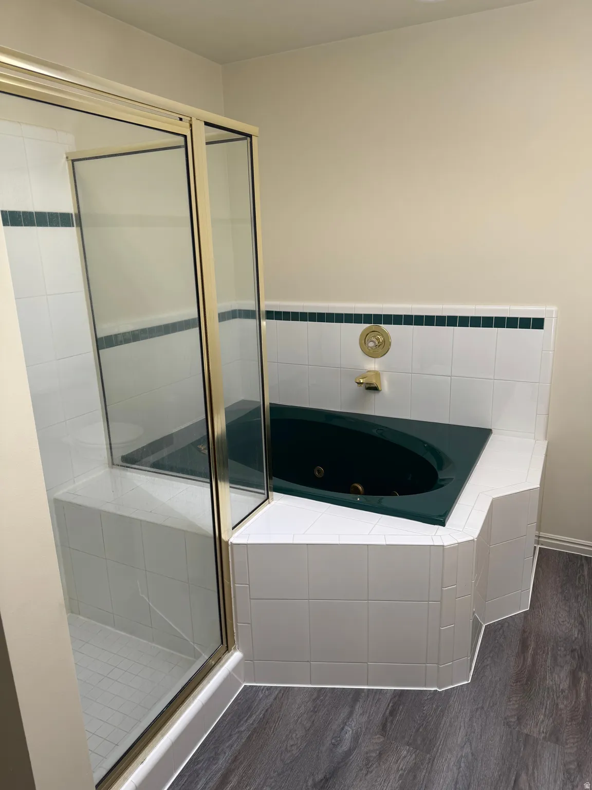 Tiled corner soaking tub with integrated jets and gold-tone fixtures