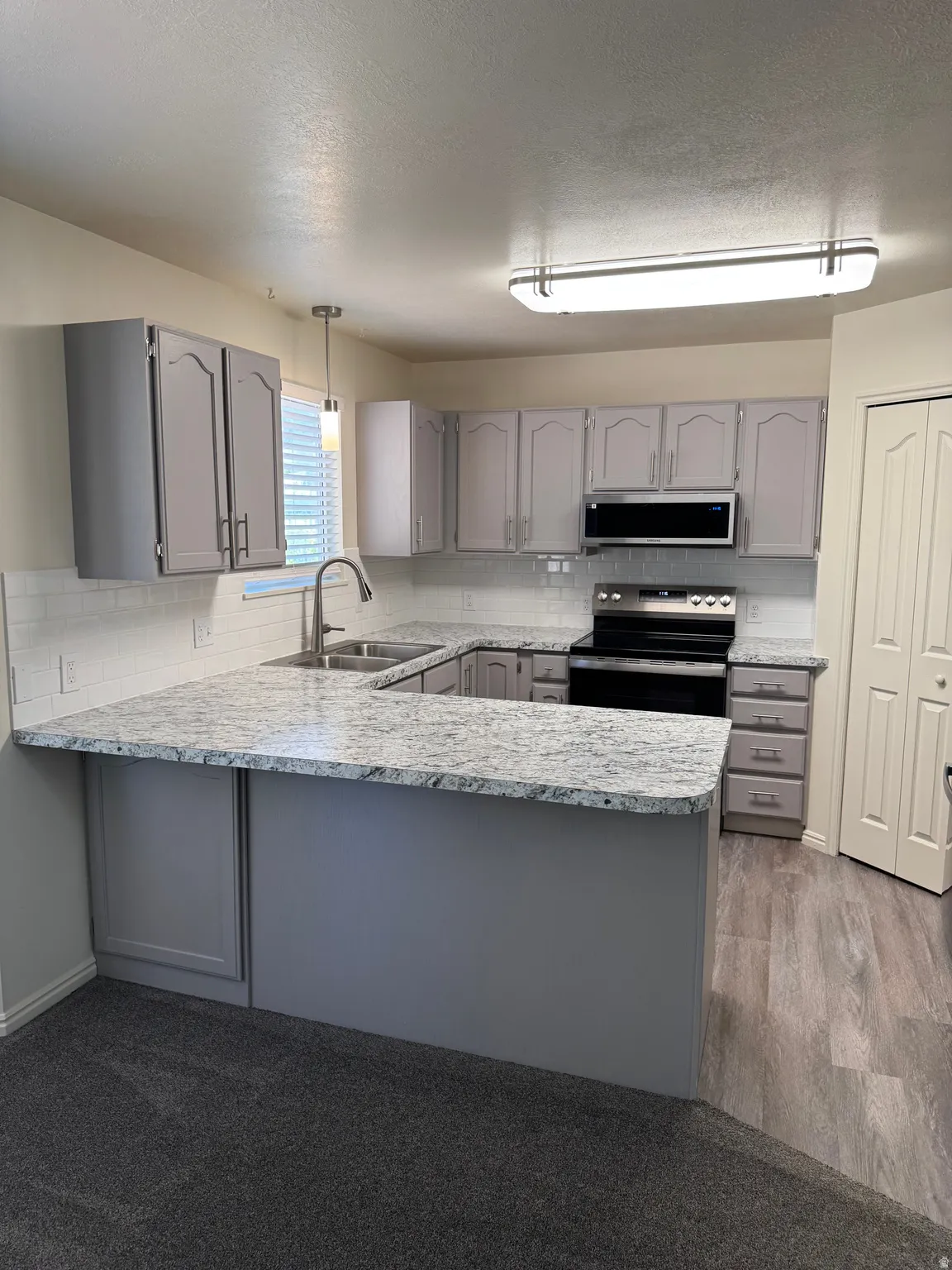 Kitchen featuring gray cabinetry, white subway tile backsplash, and light-toned countertops
