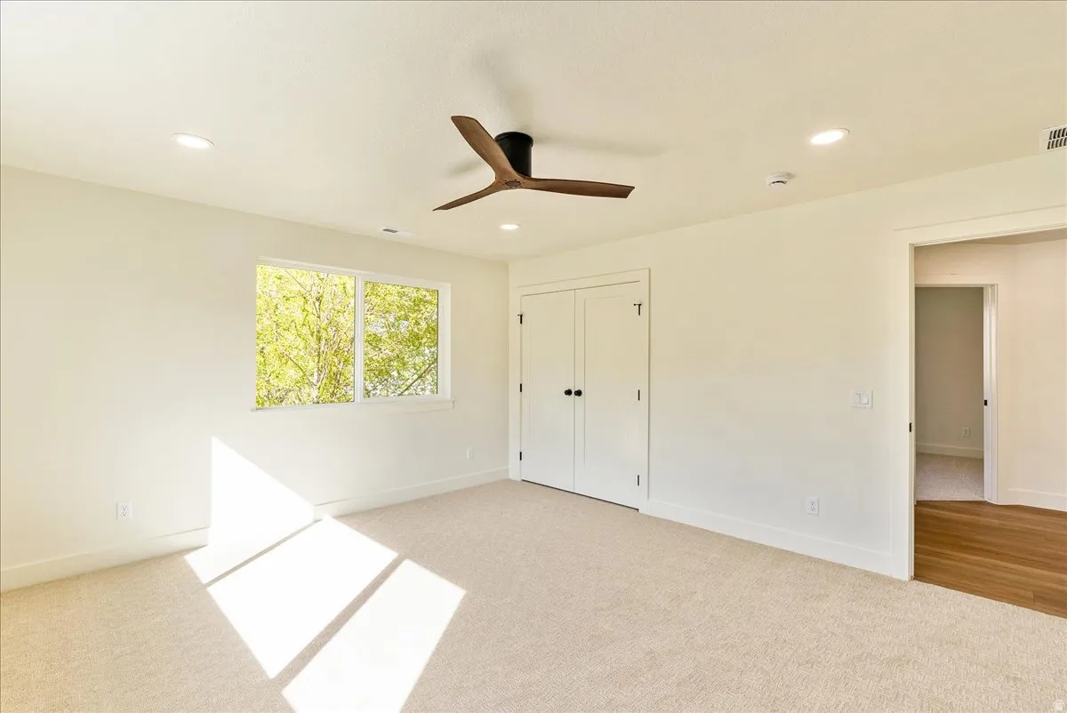 Spacious room featuring carpeted flooring, a ceiling fan with integrated lighting, recessed lighting, and a double-door closet