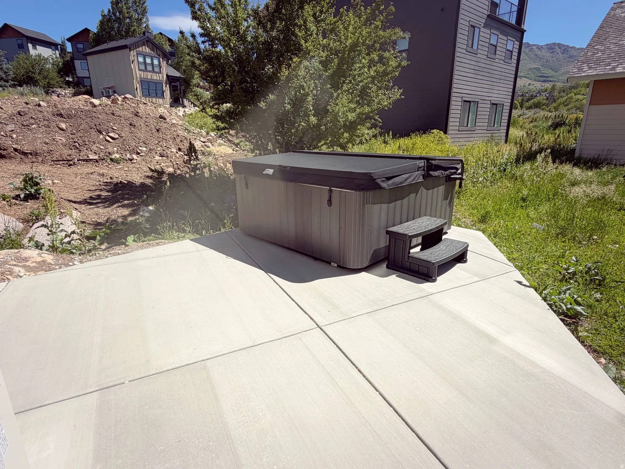 Outdoor patio featuring a hot tub with steps and a cover