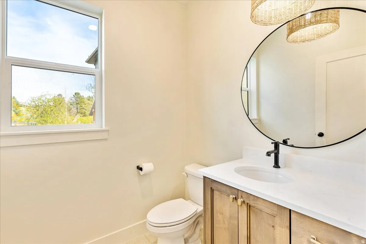 Bathroom featuring a wood-finish vanity with a white countertop, an oval mirror, and a white toilet