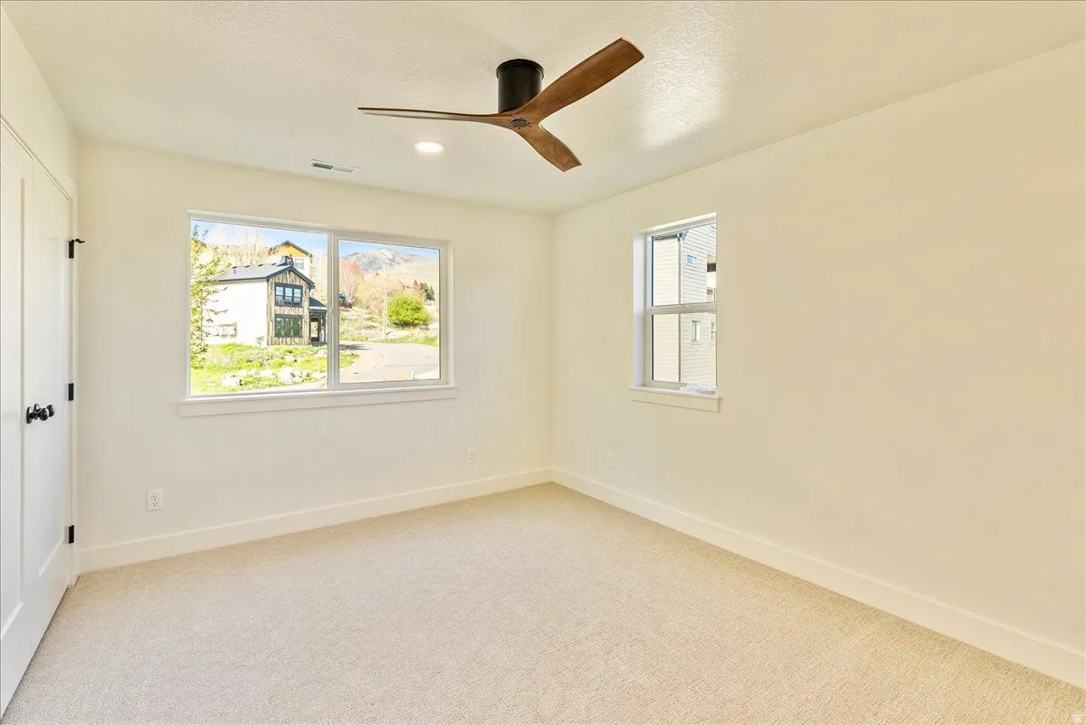 Carpeted room featuring a modern ceiling fan with wood-finish blades, recessed lighting, and white trim